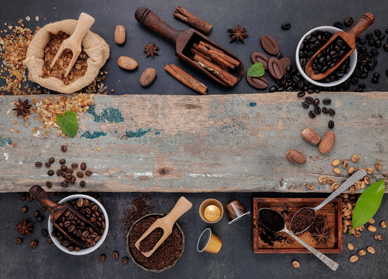 Coffee background with various of roasted coffee beans and flavourful ingredients for make tasty coffee setup on dark stone background.