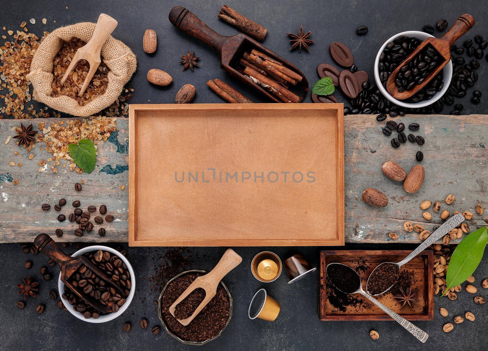 Coffee background with various of roasted coffee beans and flavourful ingredients for make tasty coffee setup on dark stone background. by kerdkanno