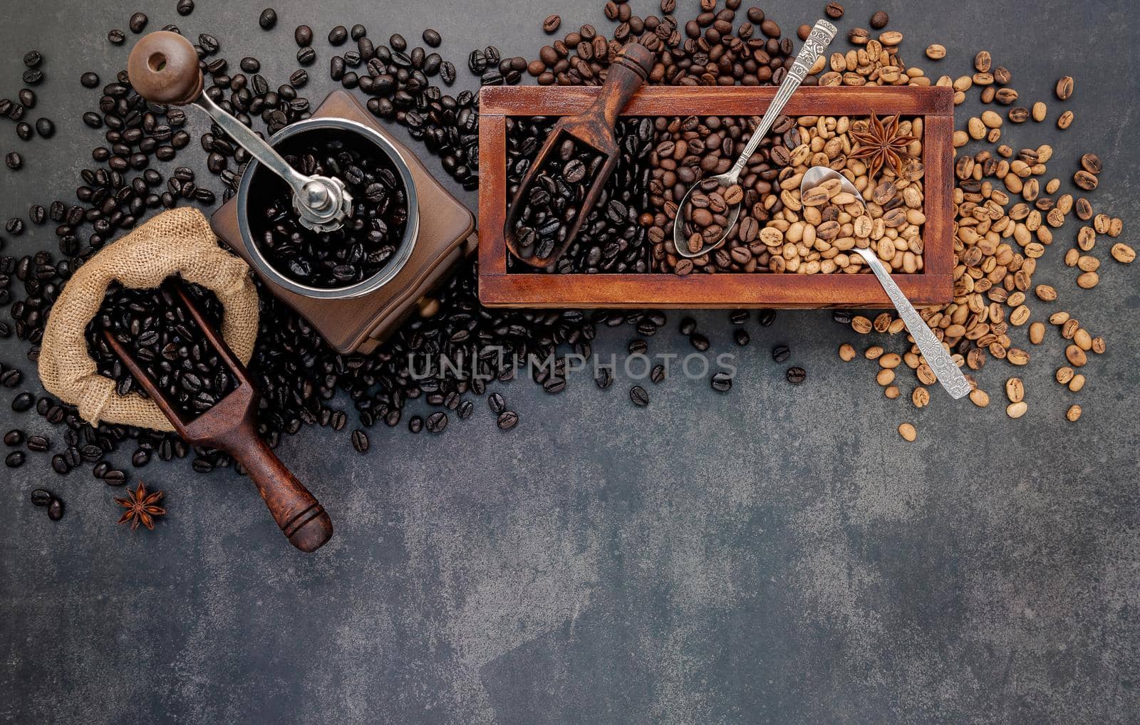 Various of roasted coffee beans in wooden box with manual coffee grinder setup on dark stone background. by kerdkanno