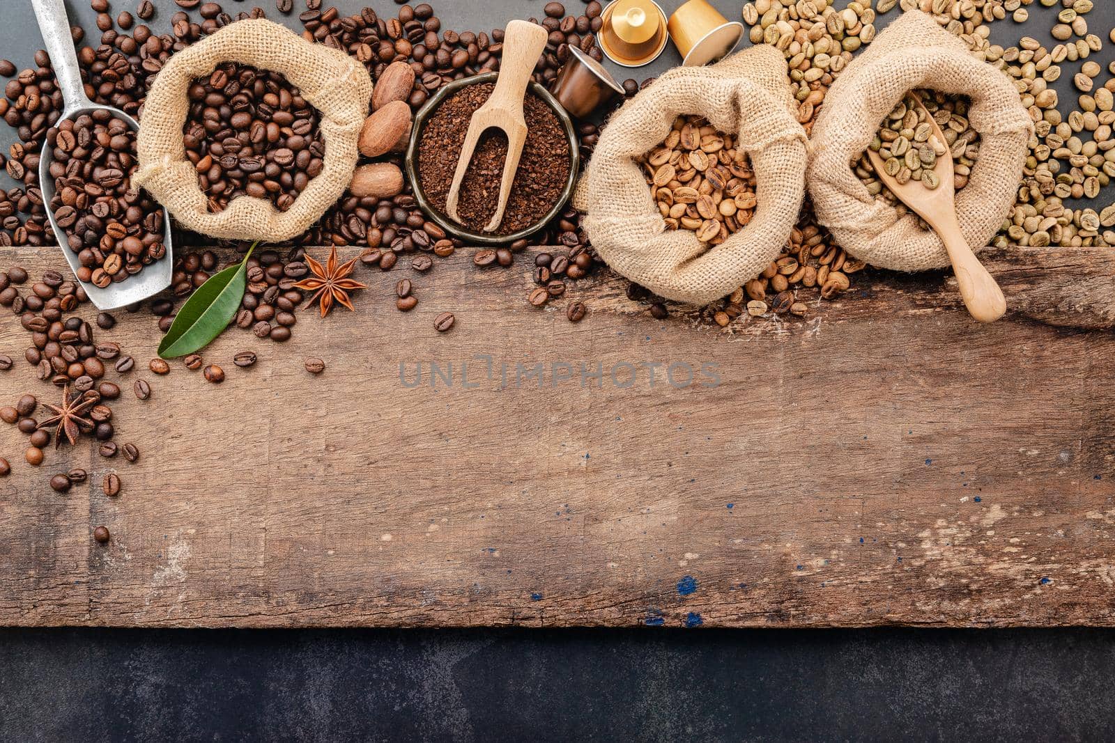 Background of various coffee , dark roasted coffee beans , ground and capsules with scoops setup on wooden background with copy space.