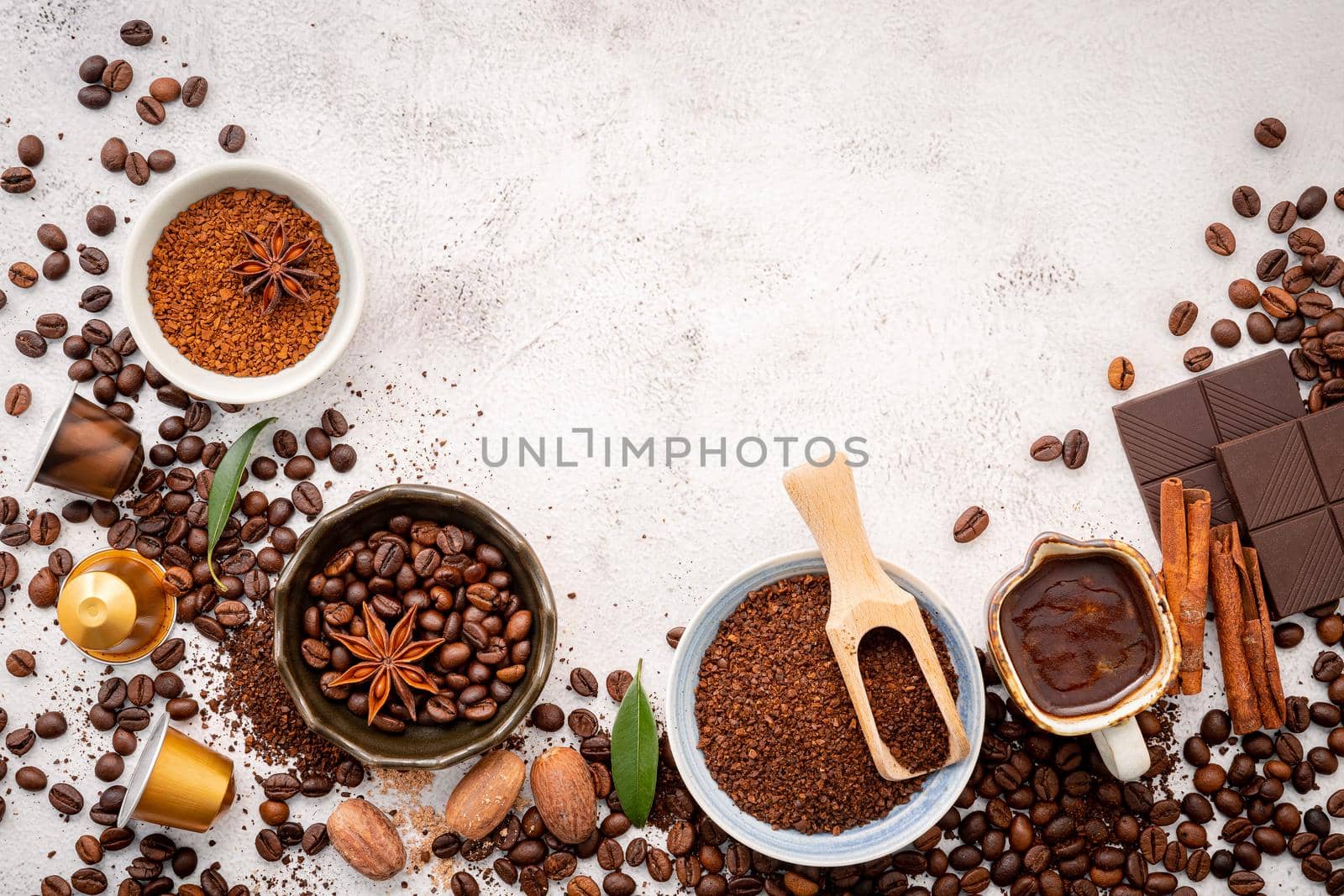 Background of various coffee , dark roasted coffee beans , ground and capsules with scoops setup on white concrete background with copy space.