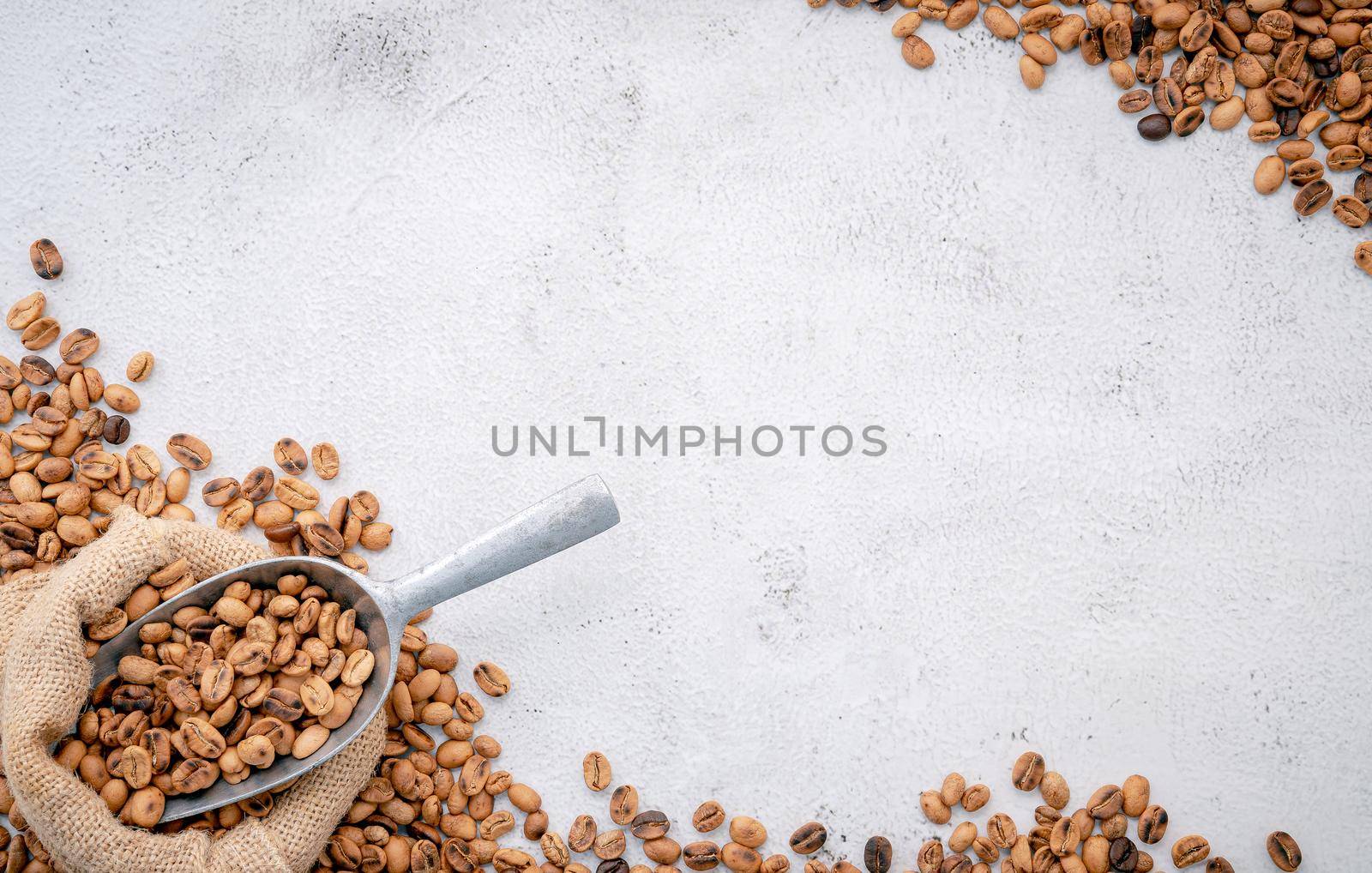 Dark roasted coffee beans in hemp sack bags with scoops setup on white concrete background. by kerdkanno