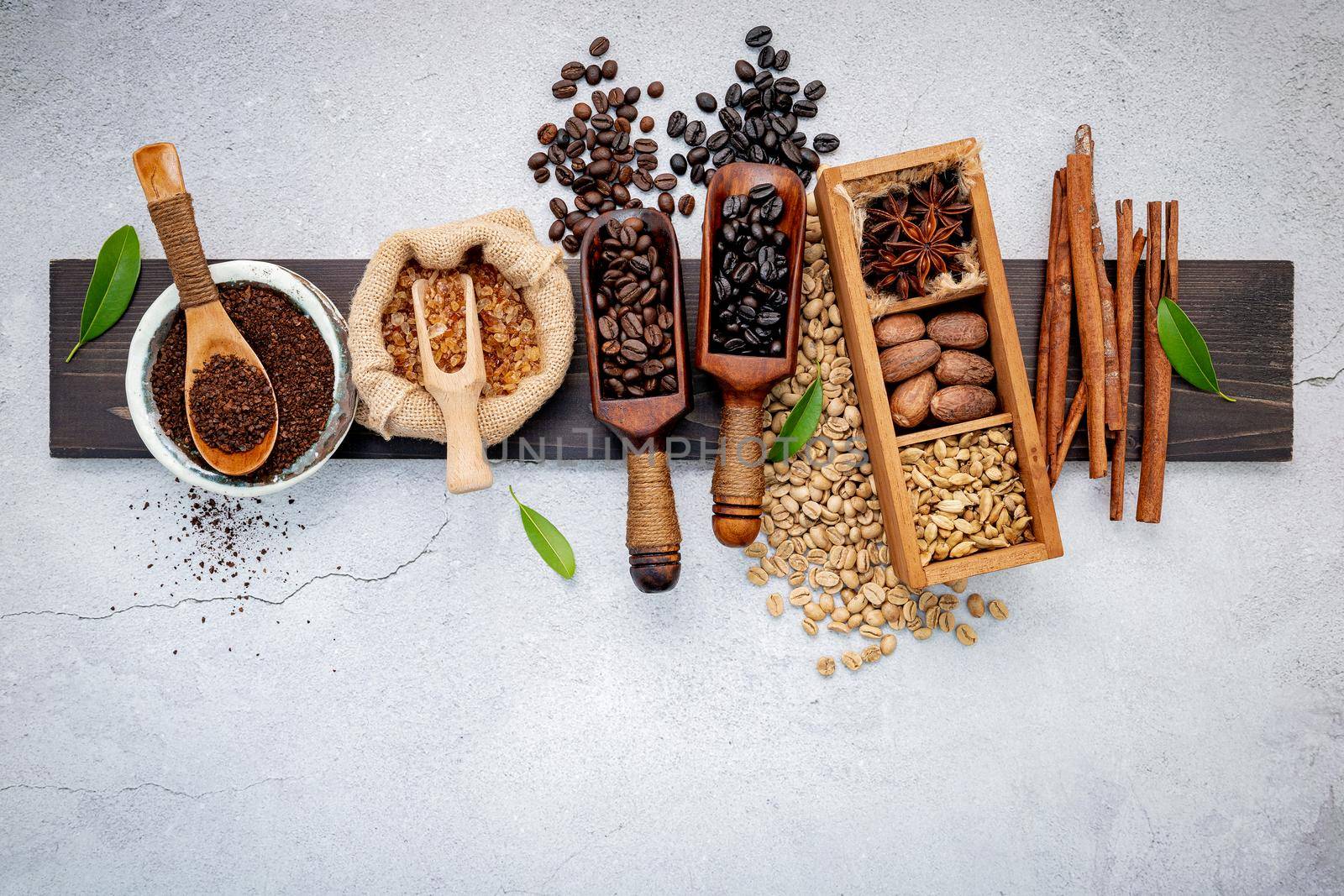 Roasted coffee beans with coffee powder and flavourful ingredients for make tasty coffee setup on dark stone background.