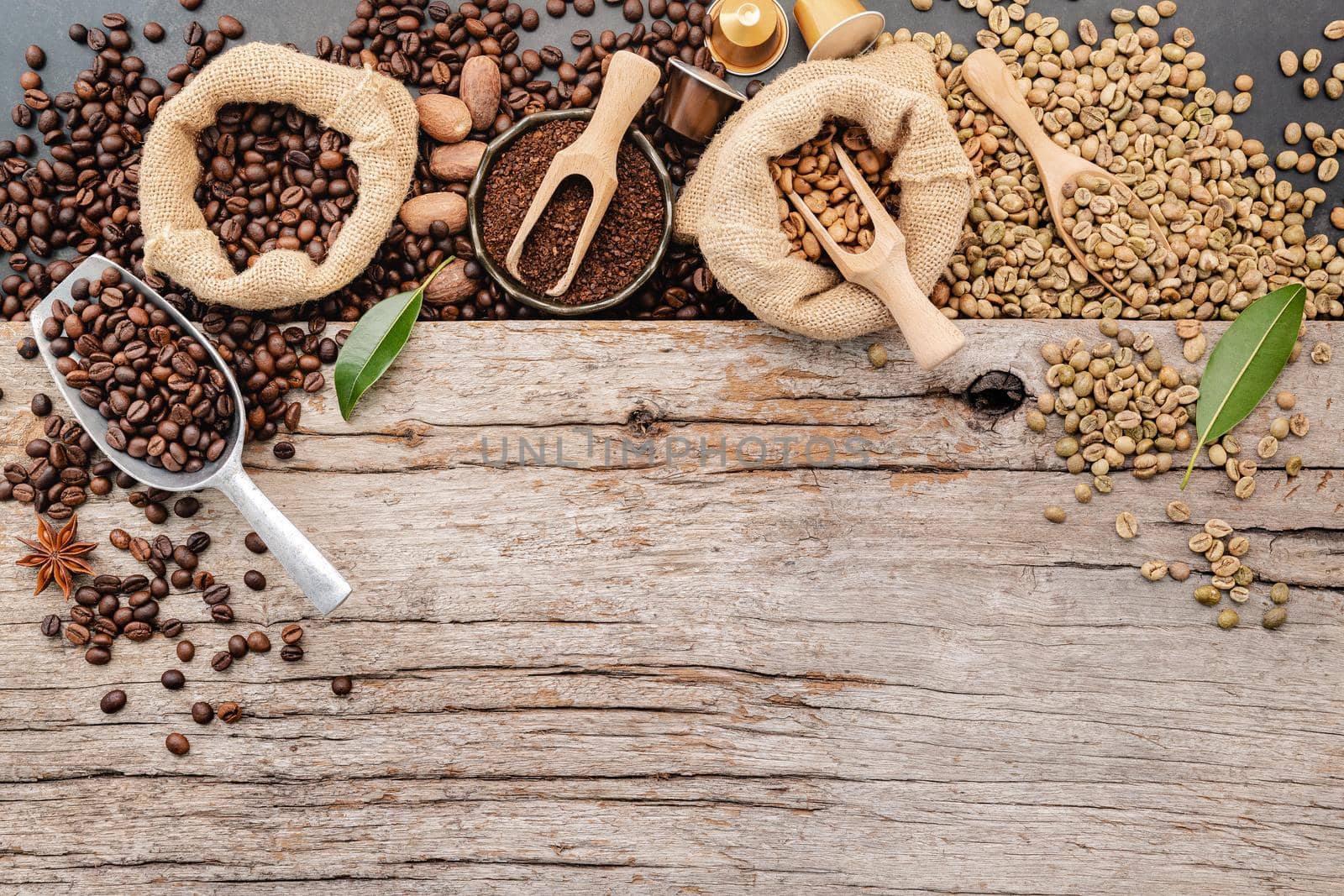 Background of various coffee , dark roasted coffee beans , ground and capsules with scoops setup on wooden background with copy space. by kerdkanno