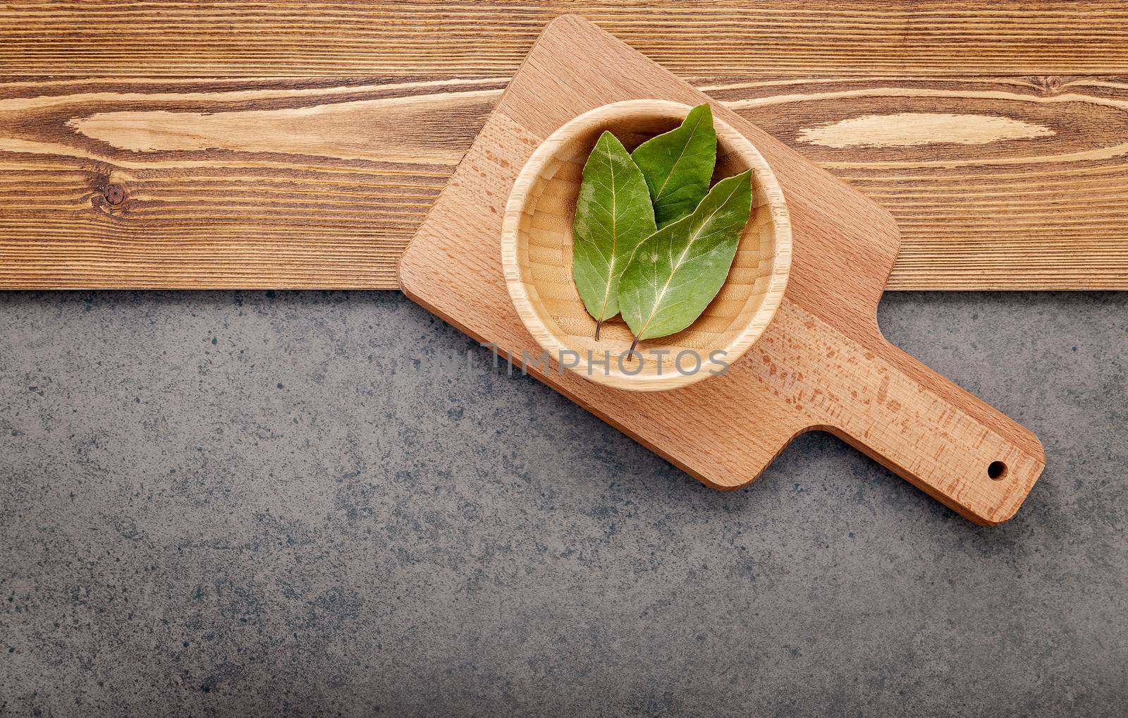 The bay leaves on cutting board set up on shabby wooden background with copy space . by kerdkanno