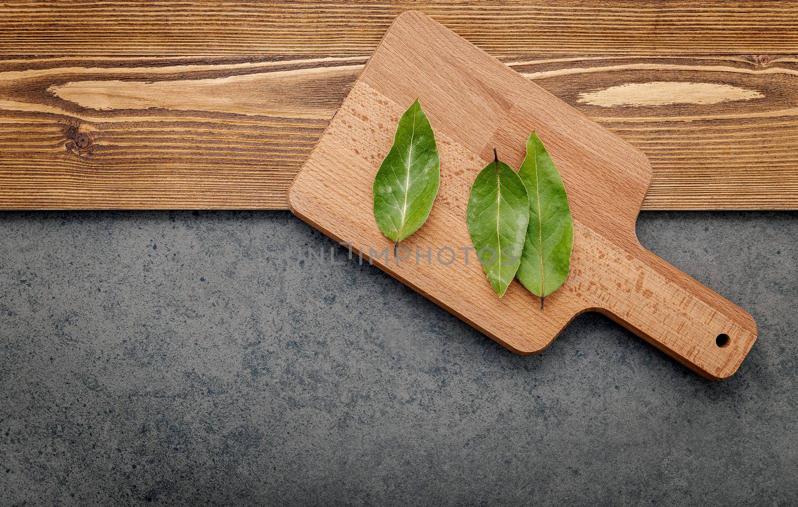 The bay leaves on cutting board set up on shabby wooden background with copy space .