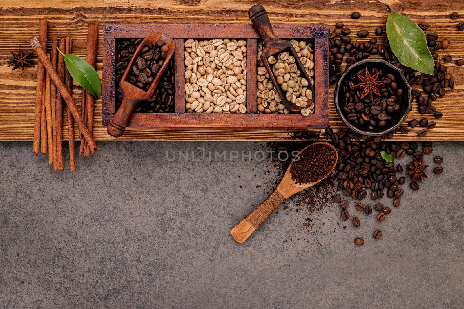 Various of roasted coffee beans in wooden box with manual coffee grinder setup on shabby wooden background.