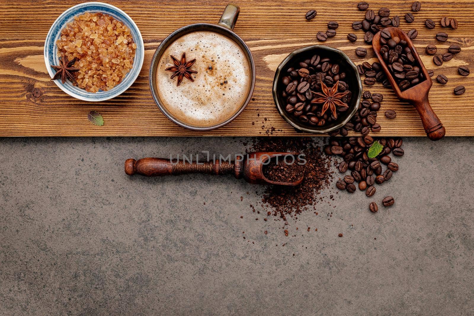 Roasted coffee beans with coffee cup setup on dark stone background.