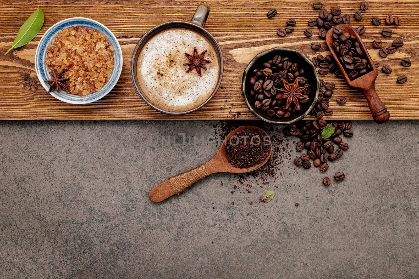 Roasted coffee beans with coffee cup setup on dark stone background.