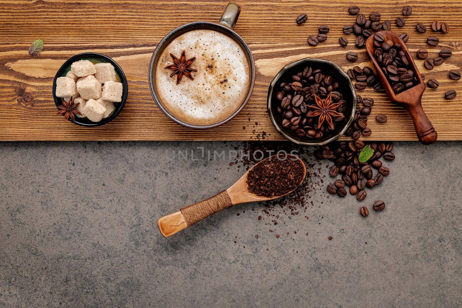 Roasted coffee beans with coffee cup setup on dark stone background.