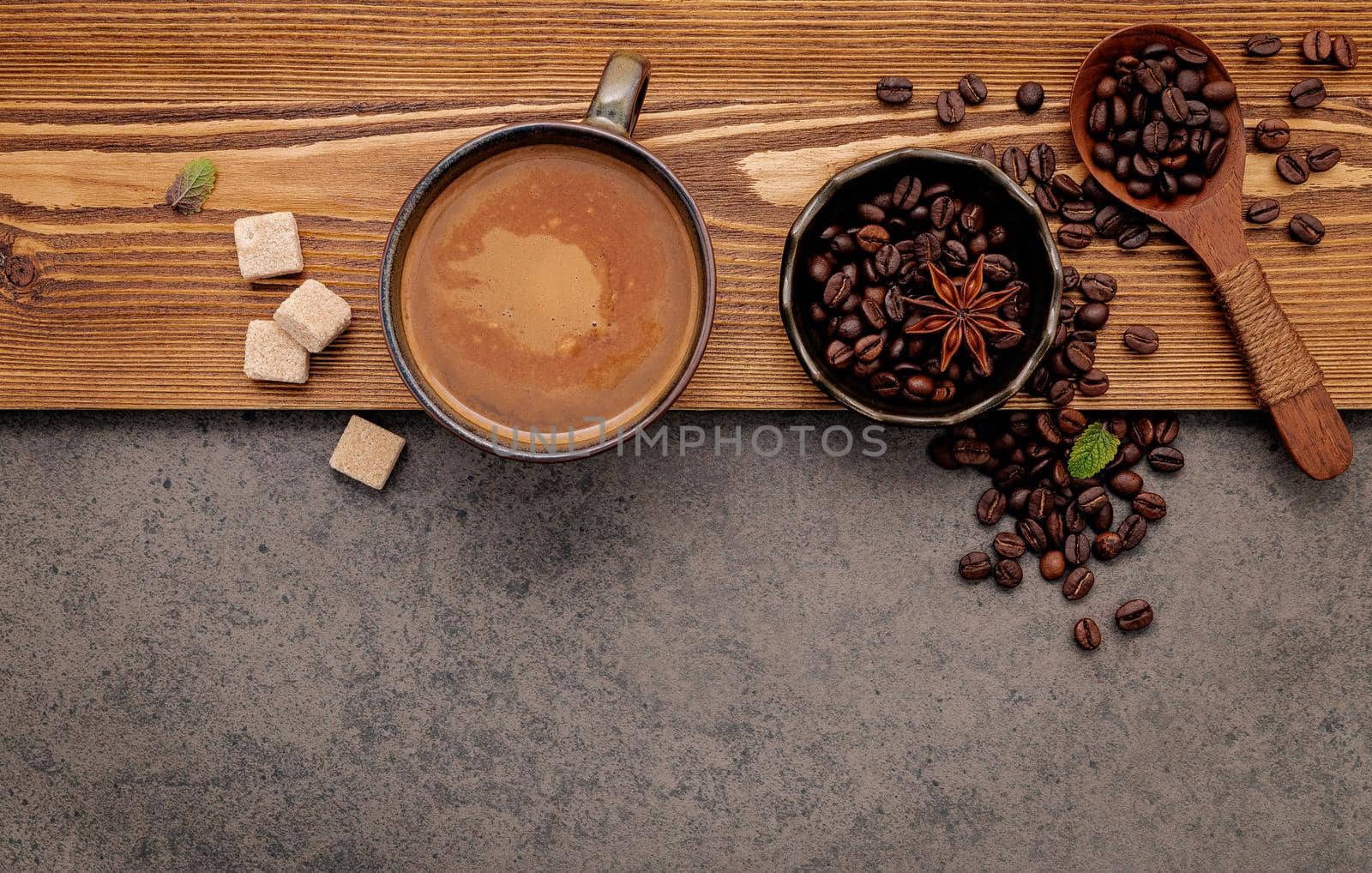 Roasted coffee beans with coffee cup setup on dark stone background.