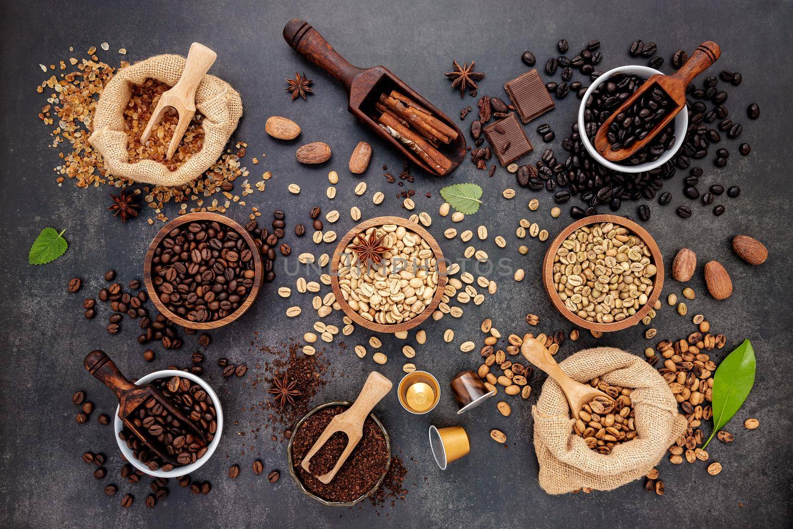 Coffee background with various of roasted coffee beans and flavourful ingredients for make tasty coffee setup on dark stone background.