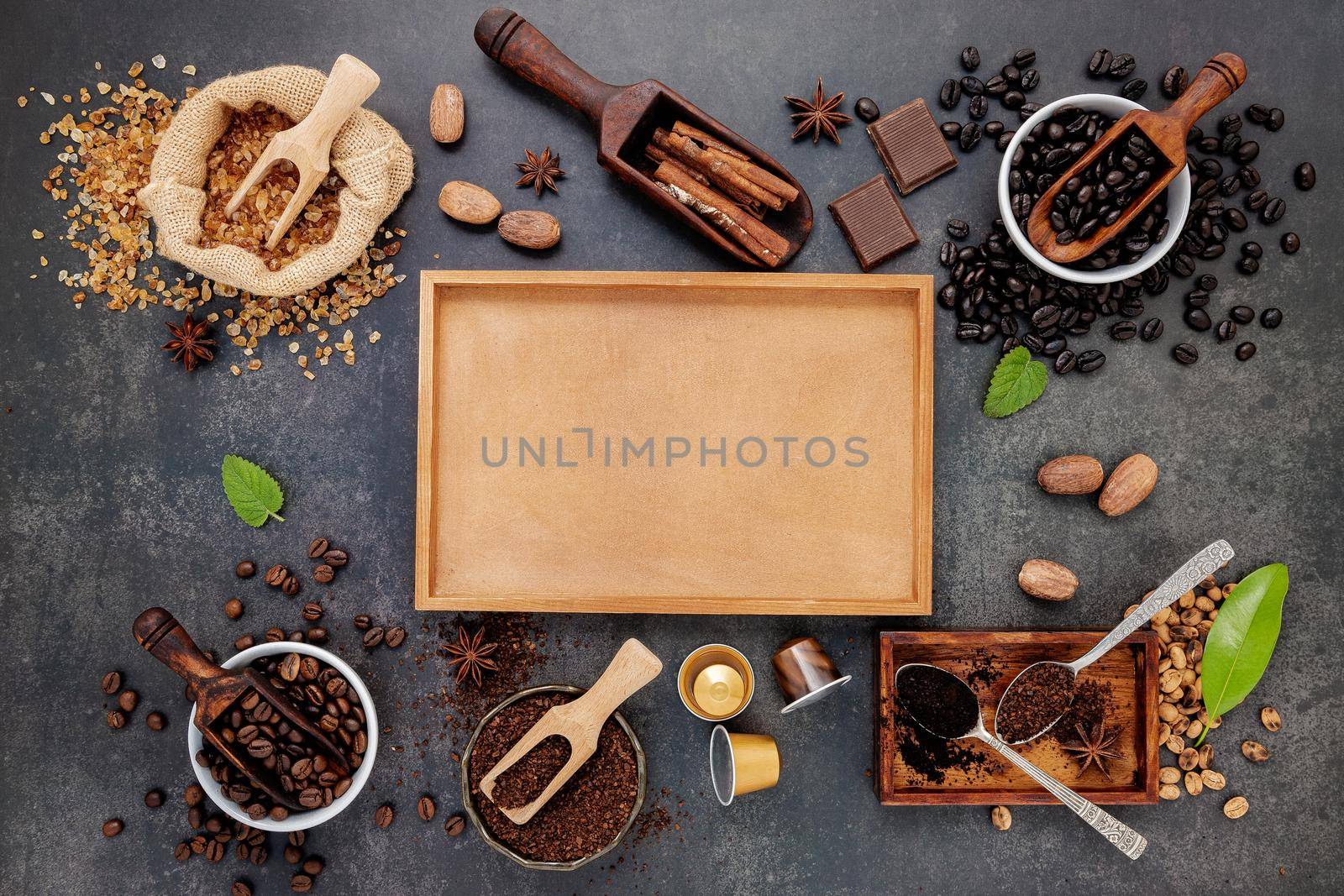 Coffee background with various of roasted coffee beans and flavourful ingredients for make tasty coffee setup on dark stone background. by kerdkanno