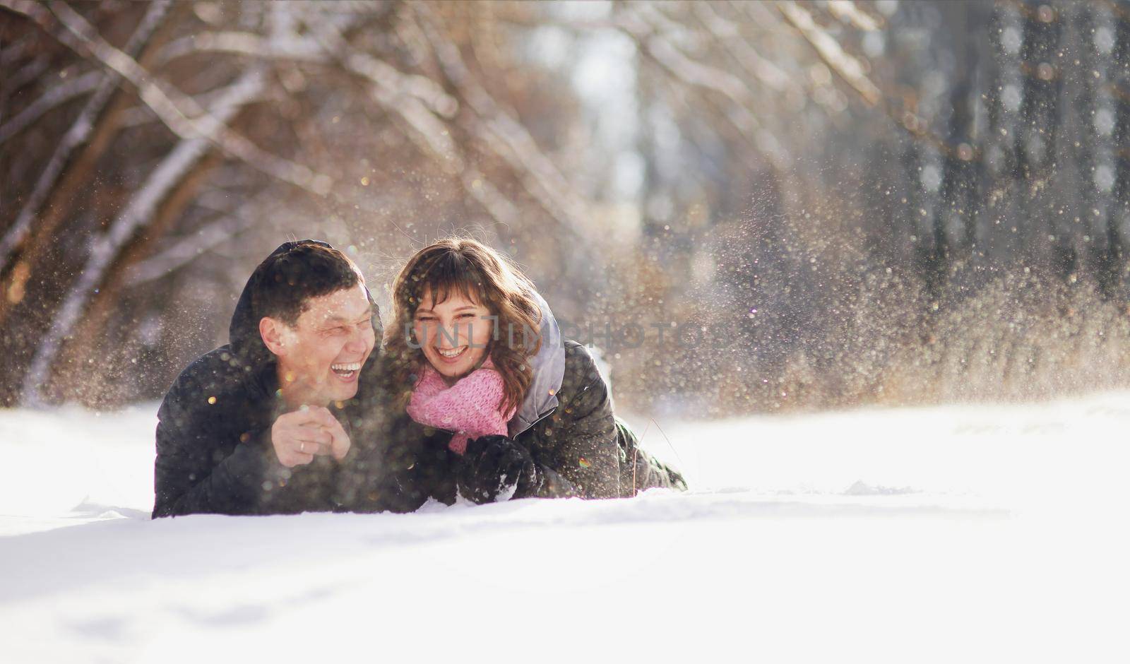 Happy couple lying on the snow and laughing. 