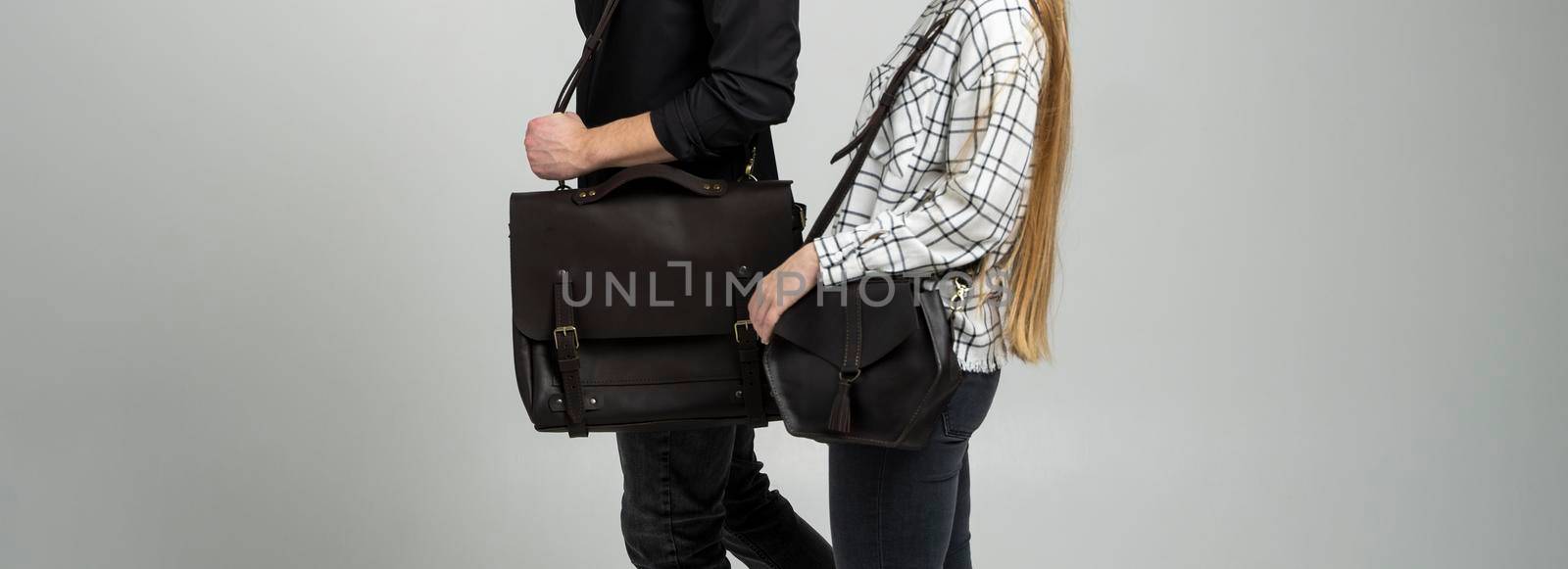 Brown men's shoulder leather bag for a documents and laptop holds by man in a black shirt and woman with a black small bag. Style, retro, fashion, vintage and elegance. by vovsht