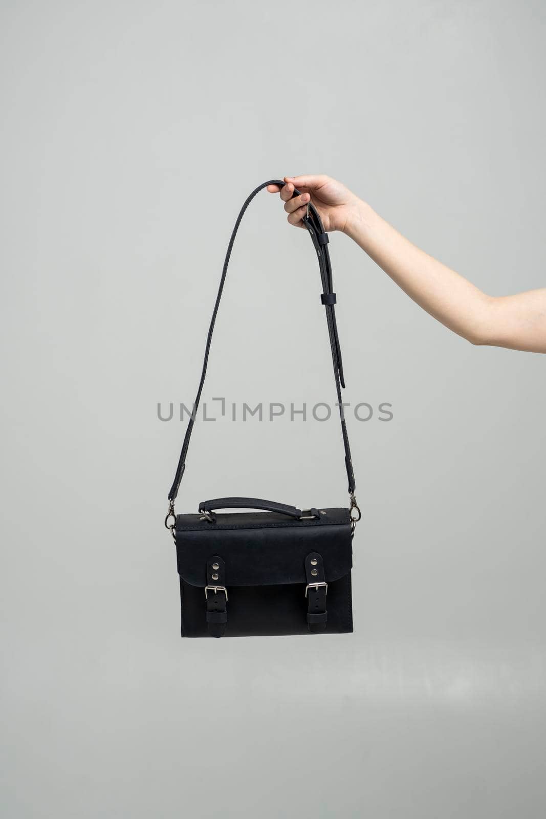 Small black leather bag in a woman's hand on a white background. Shoulder handbag. Style, retro, fashion, vintage and elegance