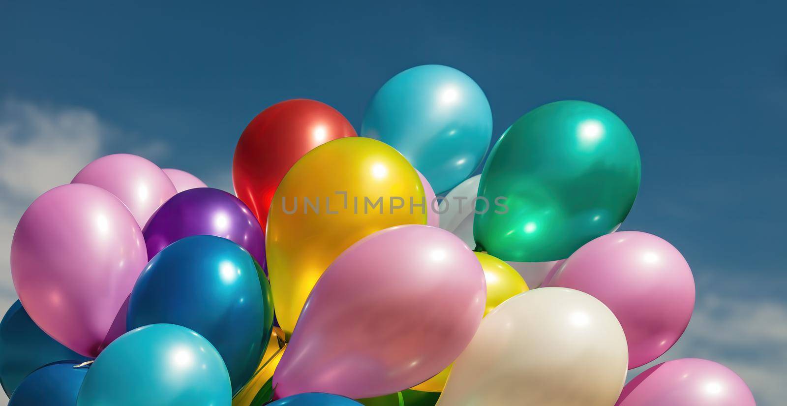 Lots of colorful balloons on the blue sky background with clouds