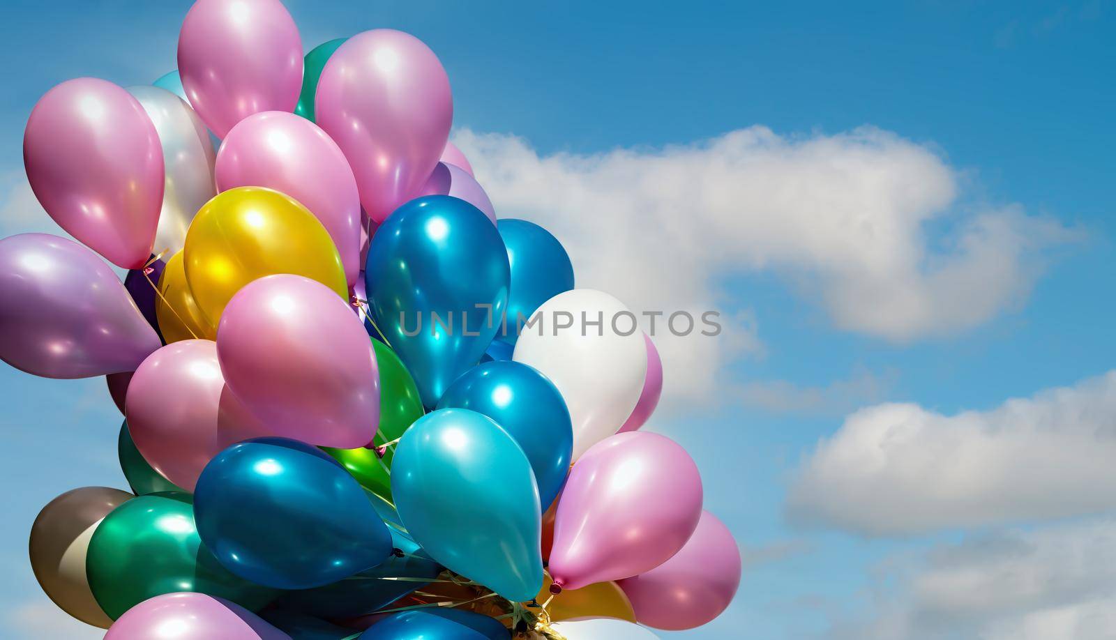 Lots of colorful balloons on the blue sky background with clouds