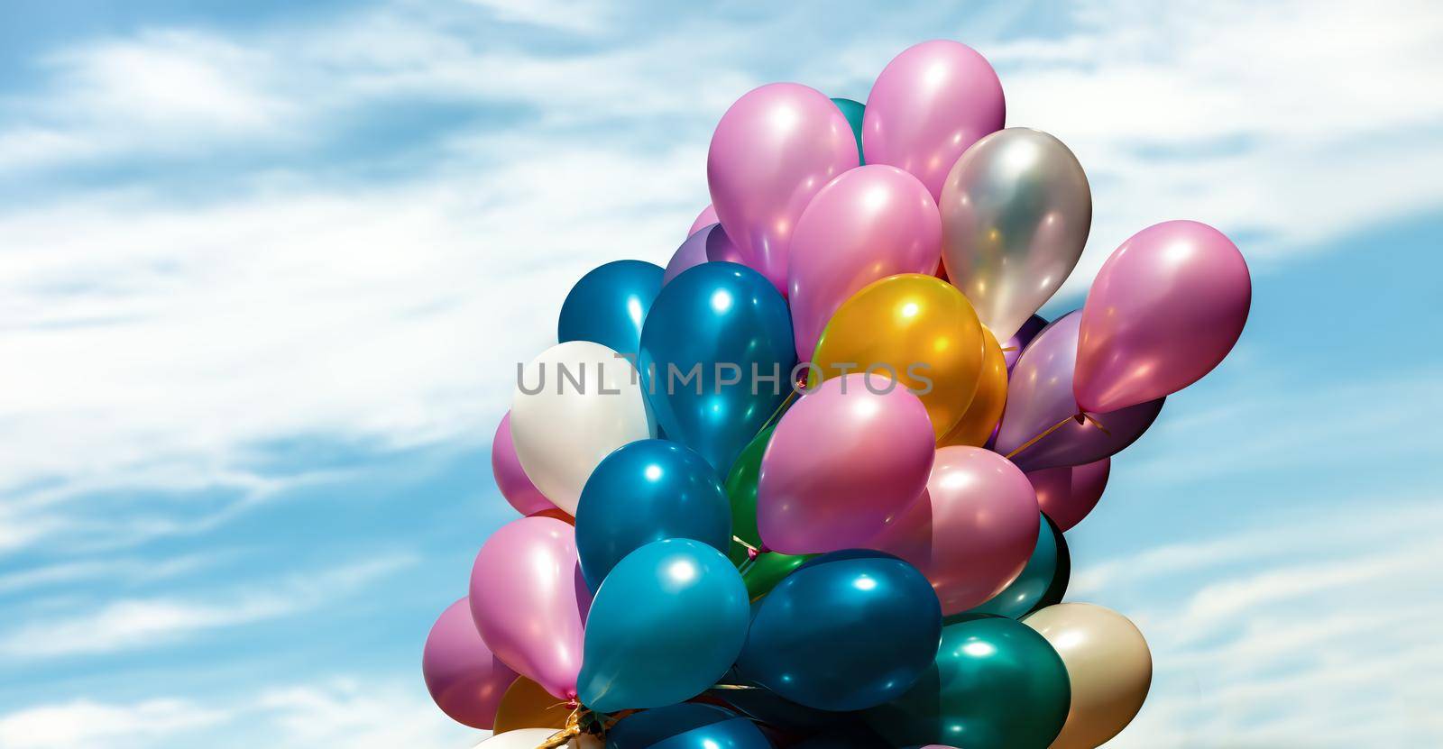 Lots of colorful balloons on the blue sky background with clouds