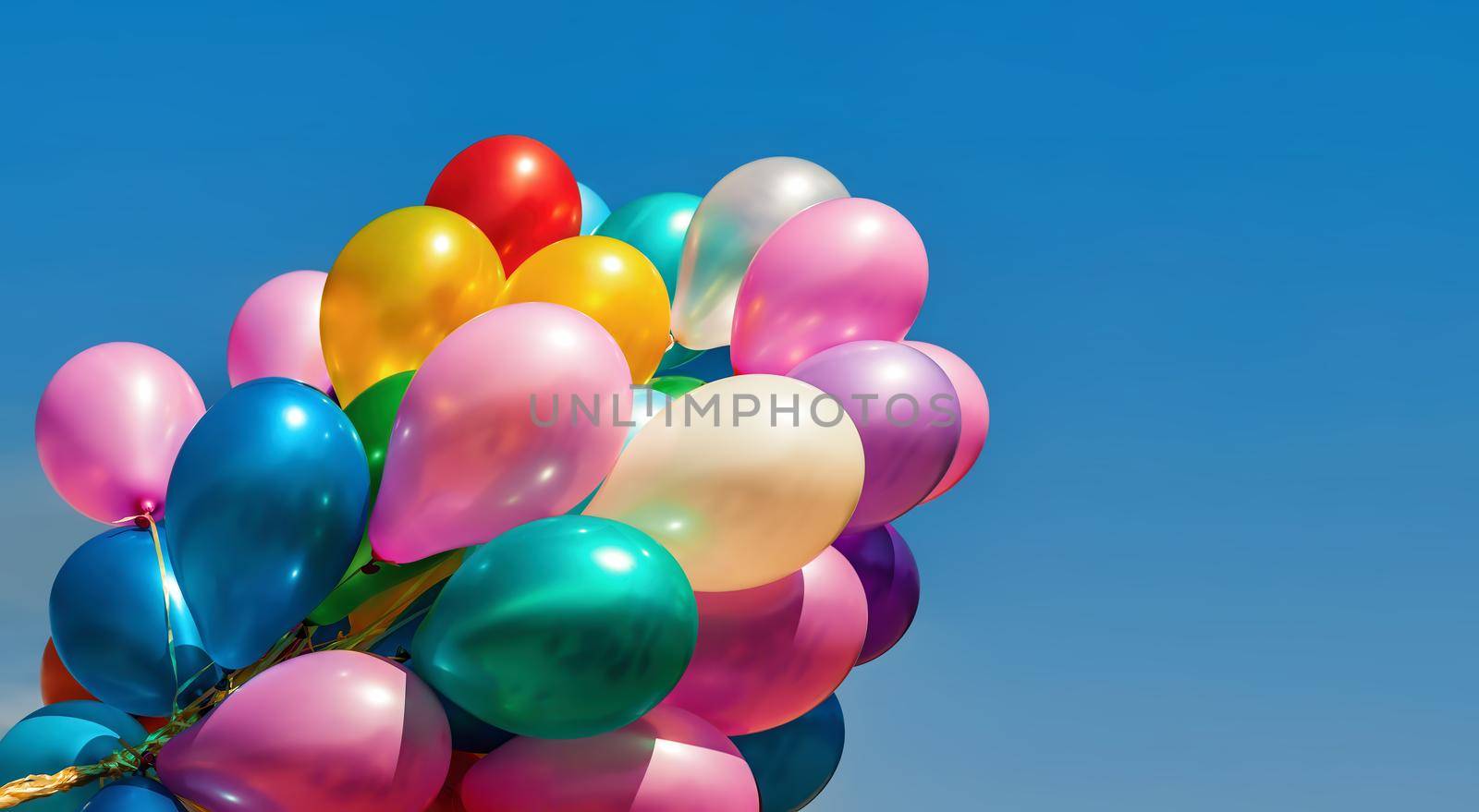 Lots of colorful balloons on the blue sky background with clouds