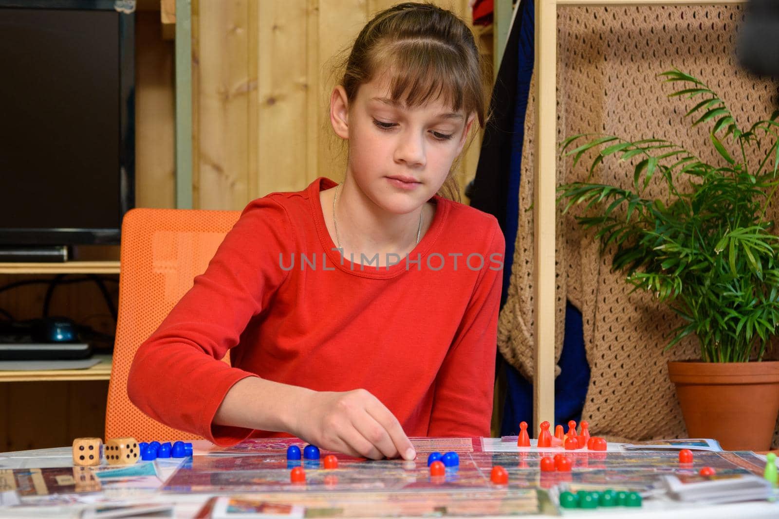 A girl makes another move with chips while playing a board game at the table