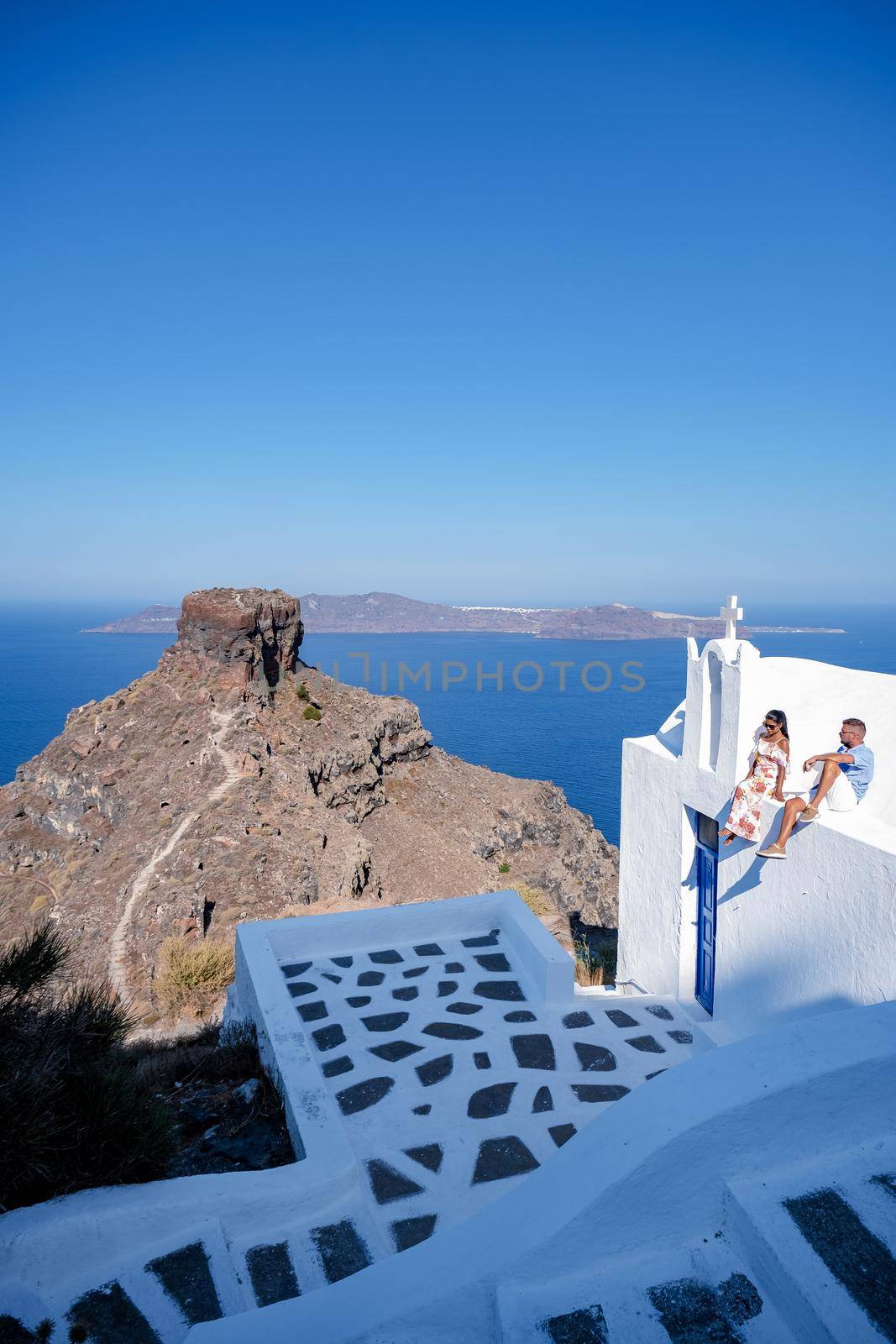 Santorini Greece, young couple mid age European and Asian on vacation at the Greek village of Oia Santorini Greece, luxury vacation Santorini. mid age man and woman watching sunset Santorini