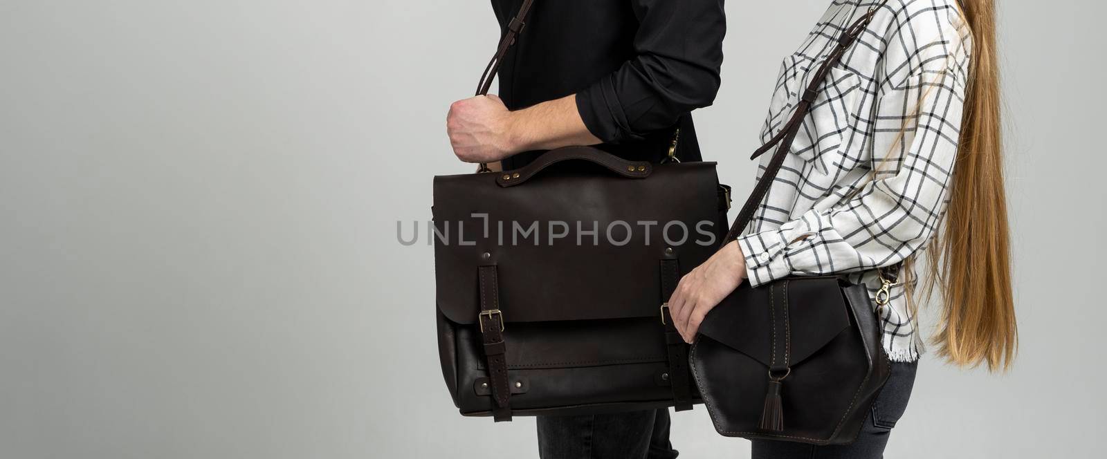Brown men's shoulder leather bag for a documents and laptop holds by man in a black shirt and woman with a black small bag. Style, retro, fashion, vintage and elegance. by vovsht