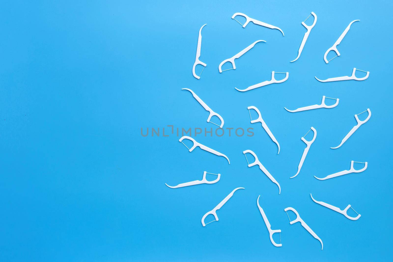 White floss toothpicks on blue background. Copy space
