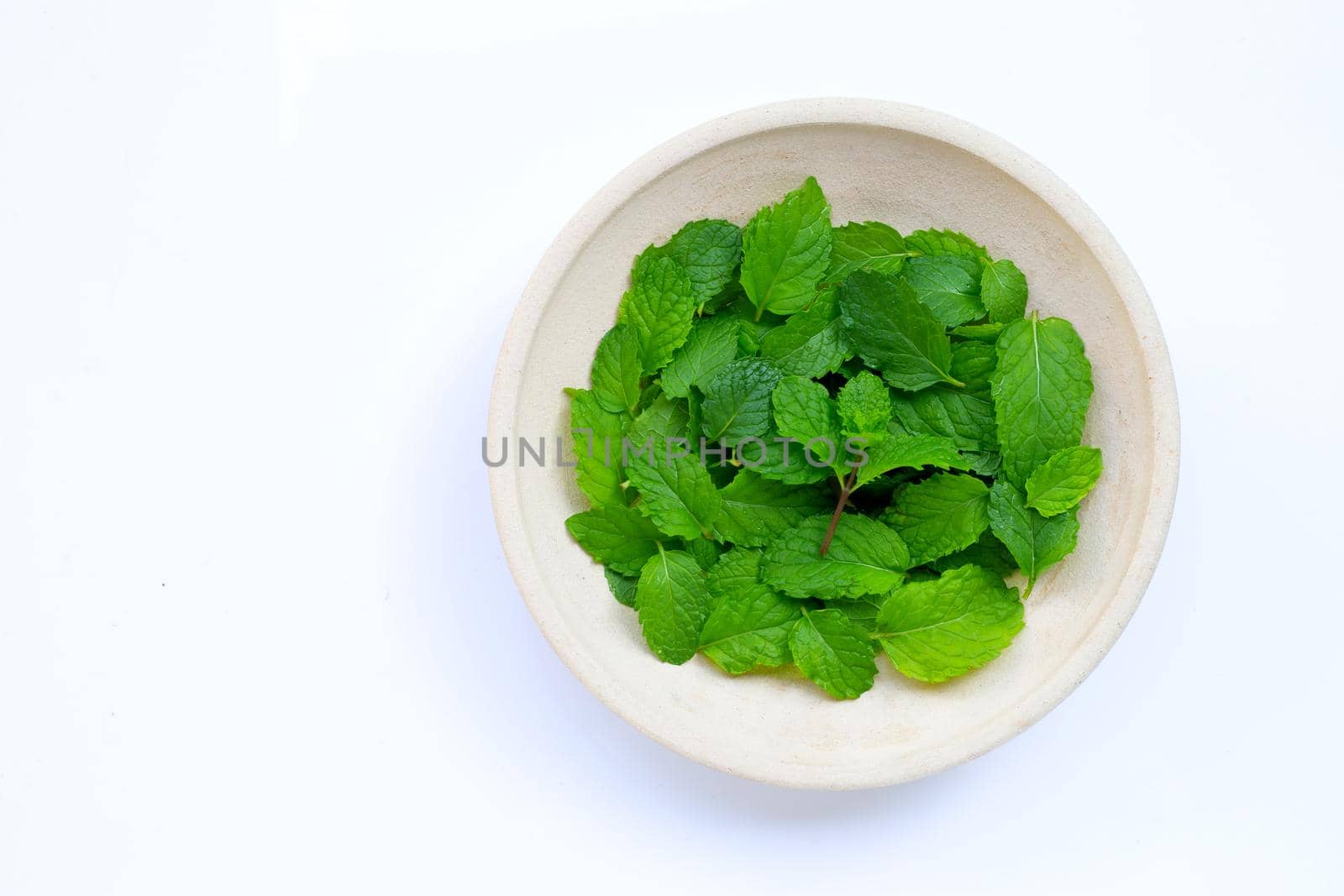 Fresh mint leaves in pottery plate on white background. Copy space