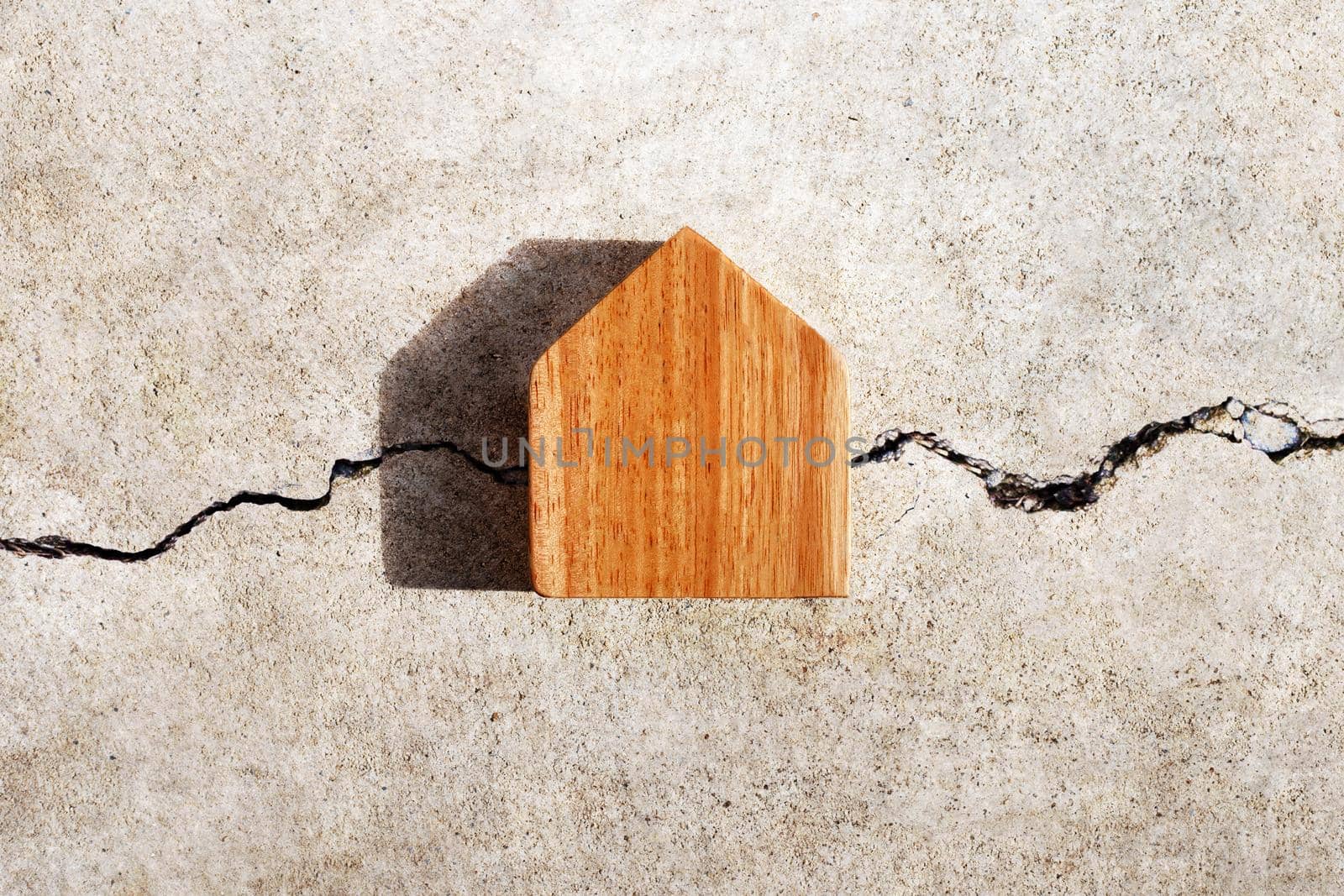 Miniature house on cracked cement wall texture background. Top view