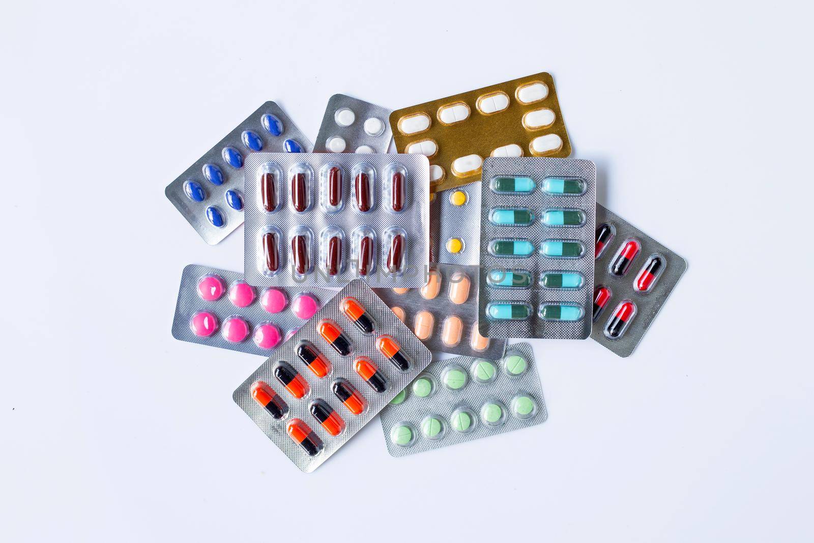 Various capsule medicines, pills and tablets in blister pack on white background.