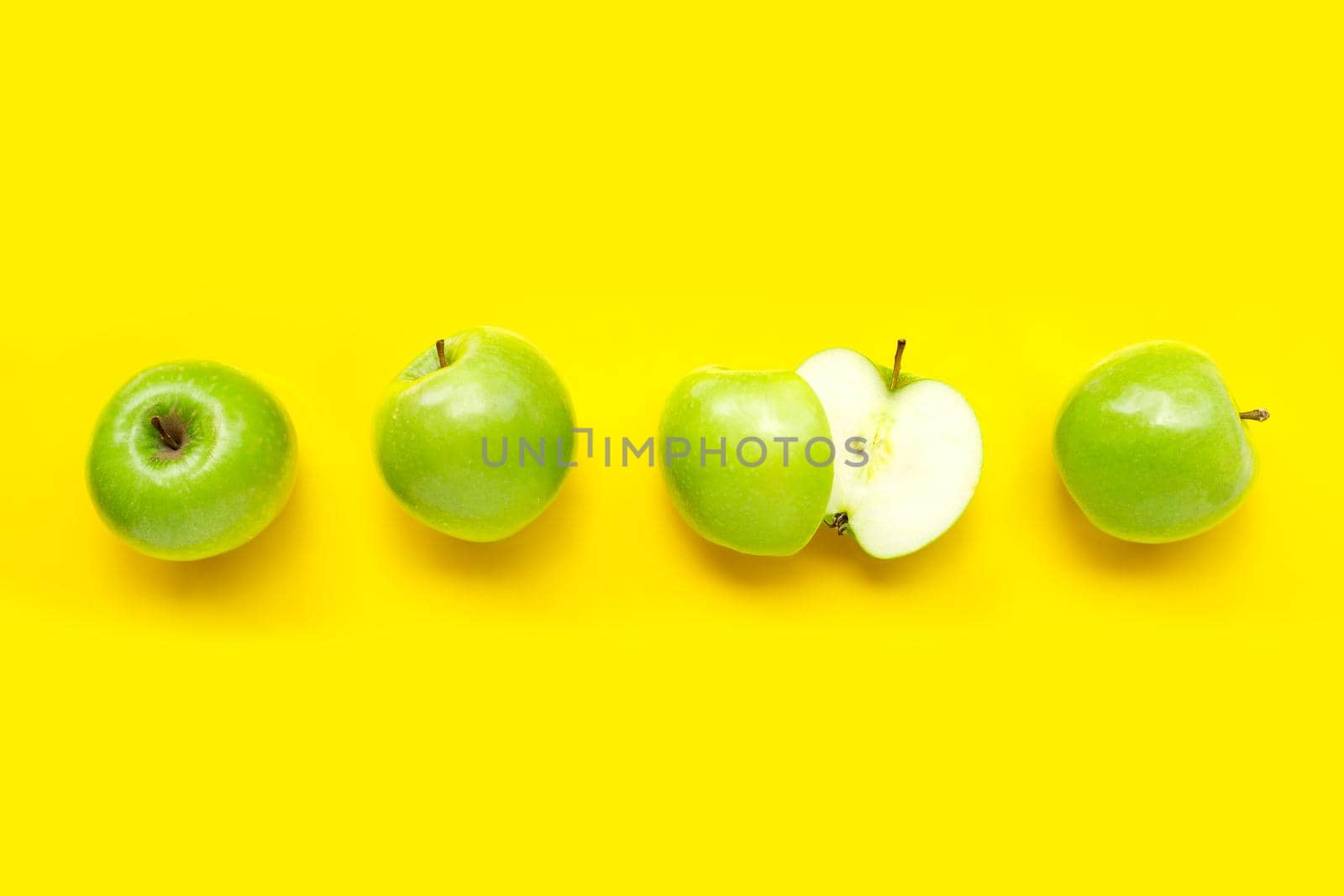 Green apples on yellow background. Top view