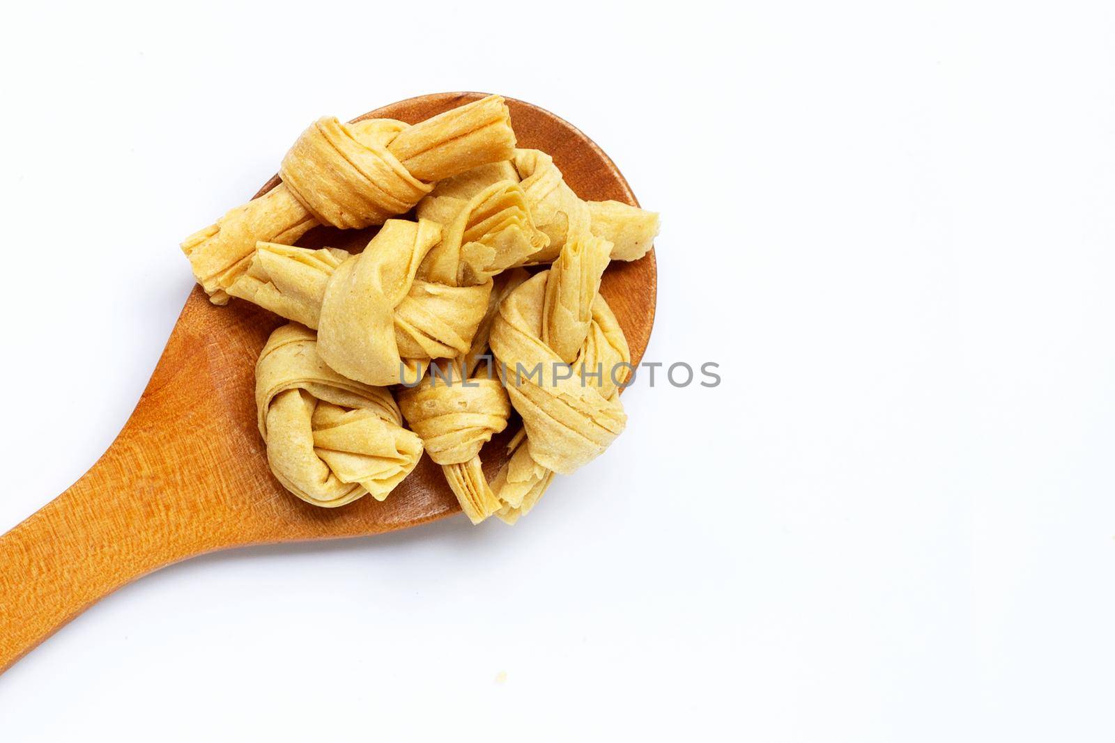 Dried bean curd knot on woon spoon on white background. Copy space