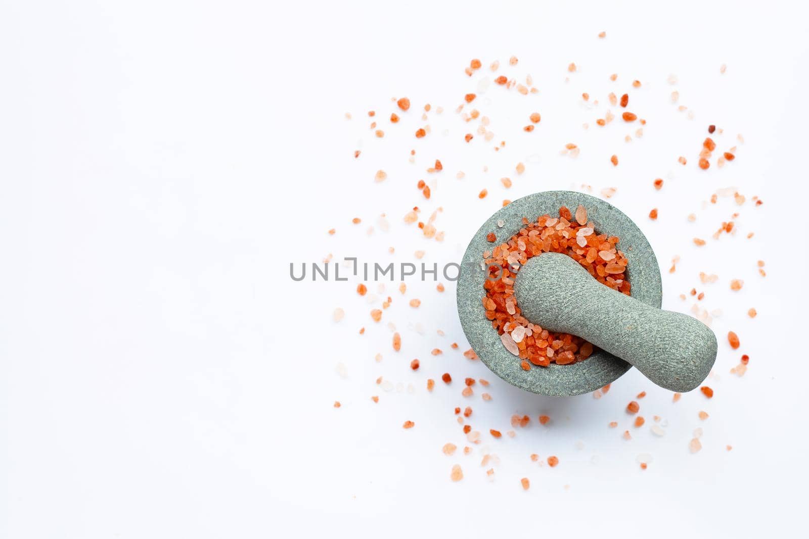 Pink himalayan salt in  stone mortar with pestle on wihte