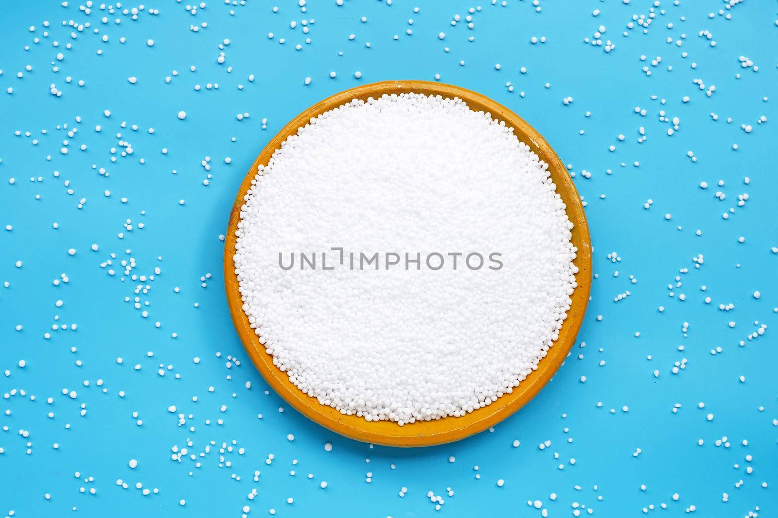 Chemical plant urea fertilizer on pottery plate on blue background. by Bowonpat