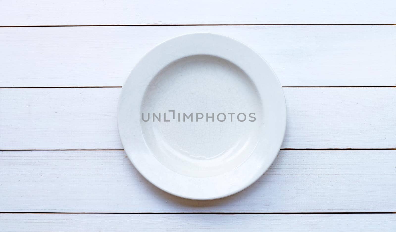 Empty white ceramic plate on white wooden background. Copy space