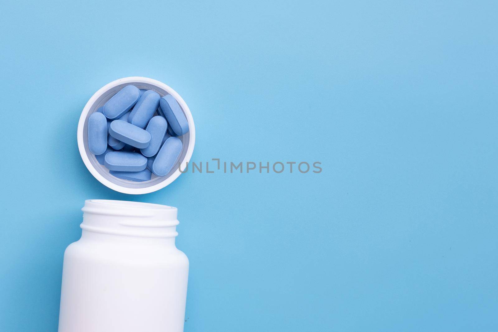PrEP ( Pre-Exposure Prophylaxis) used to prevent HIV, in plastic pill bottle cap on blue background, Copy space