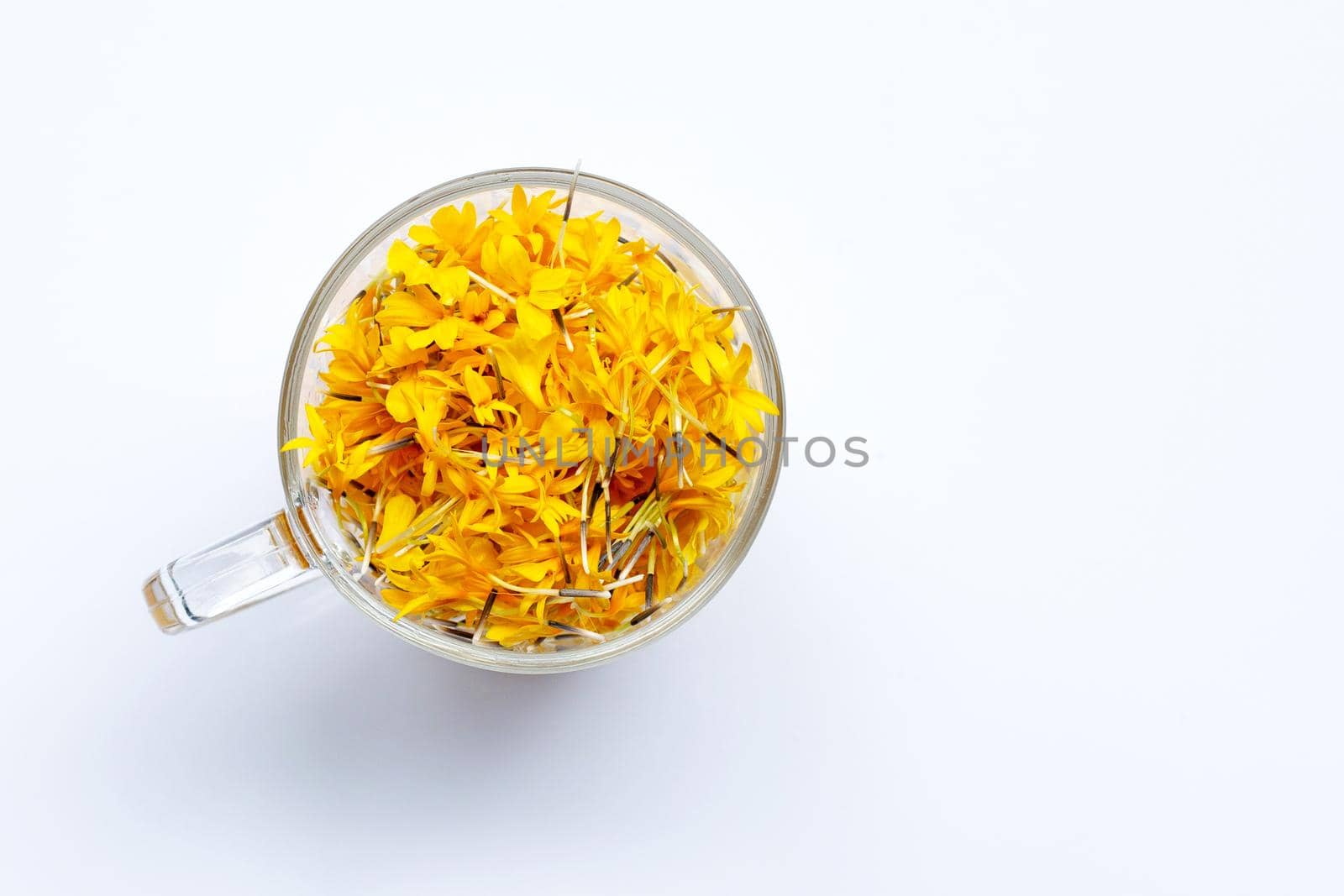 A glass cup with marigold flower petals on white background. Flower herbal tea concept.