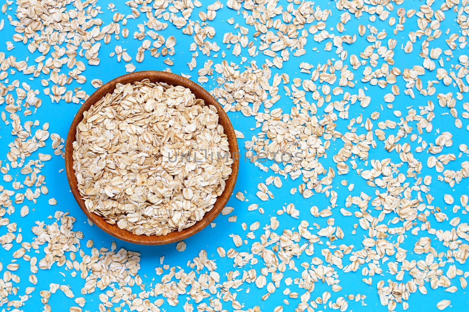 Oat flakes in bowl on blue background. Healthy food concept