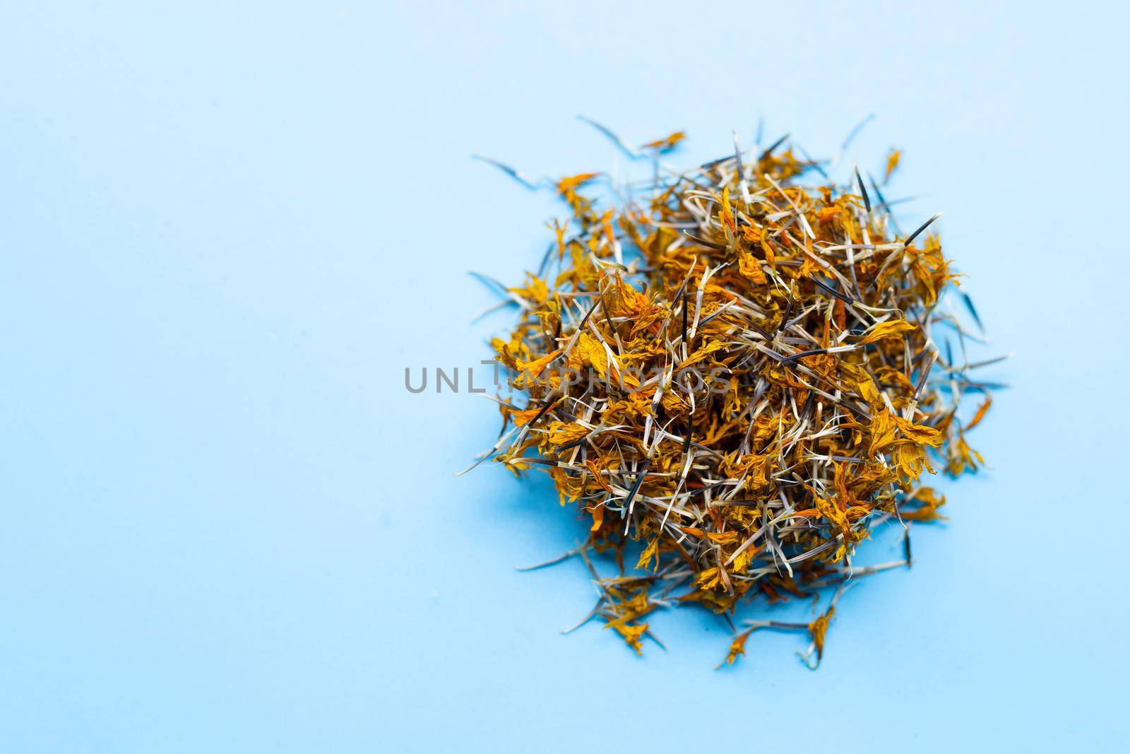 Dried marigold flower petals on blue background. Flower herbal tea concept.