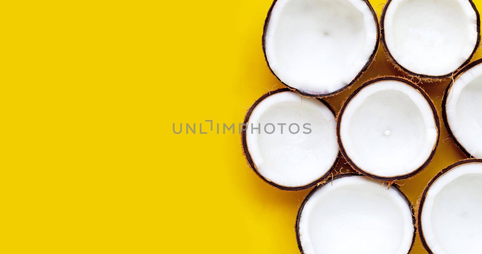 Half coconuts on yellow background. Copy space