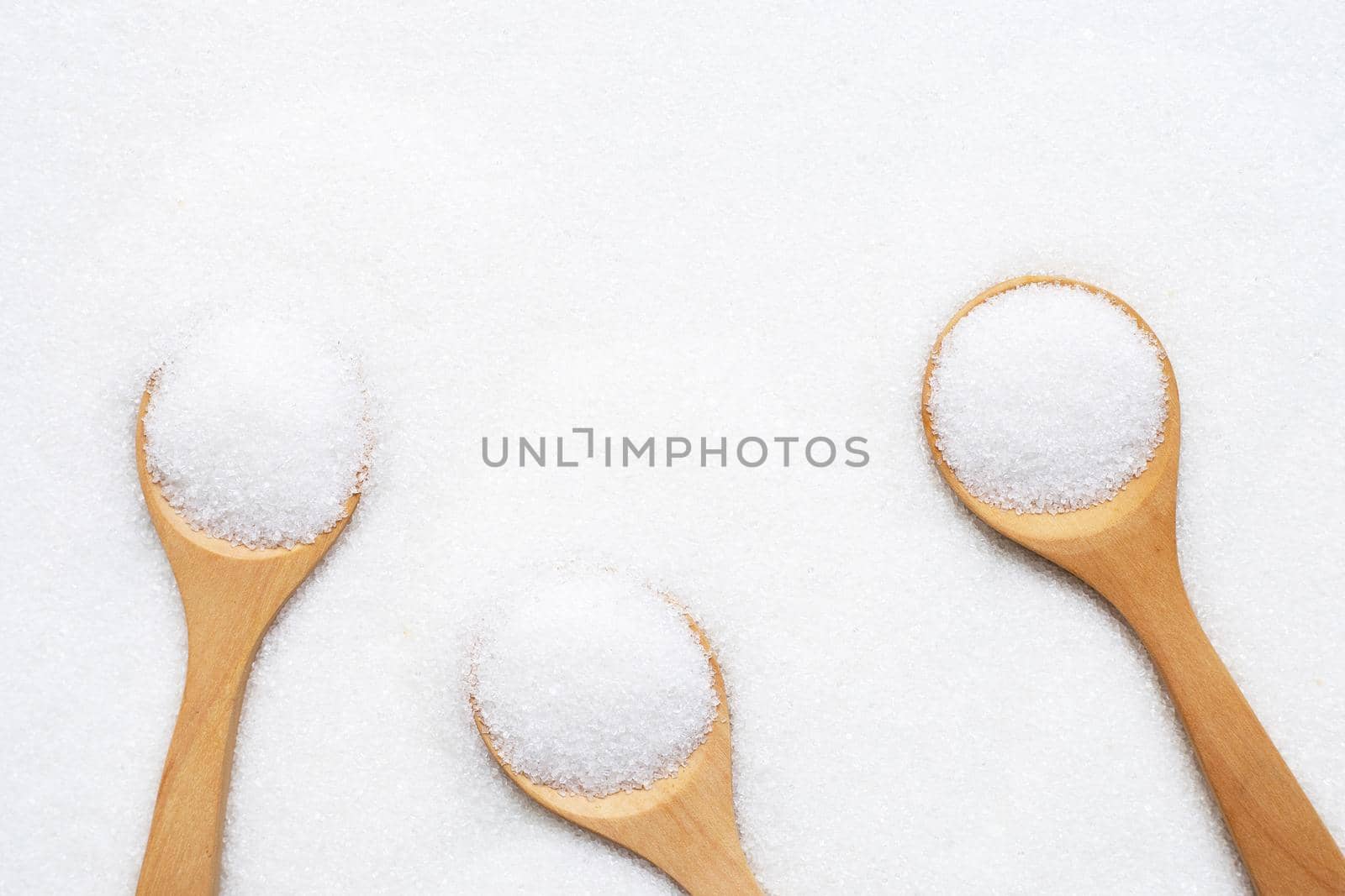 Wooden spoon with white granulated sugar. Top view