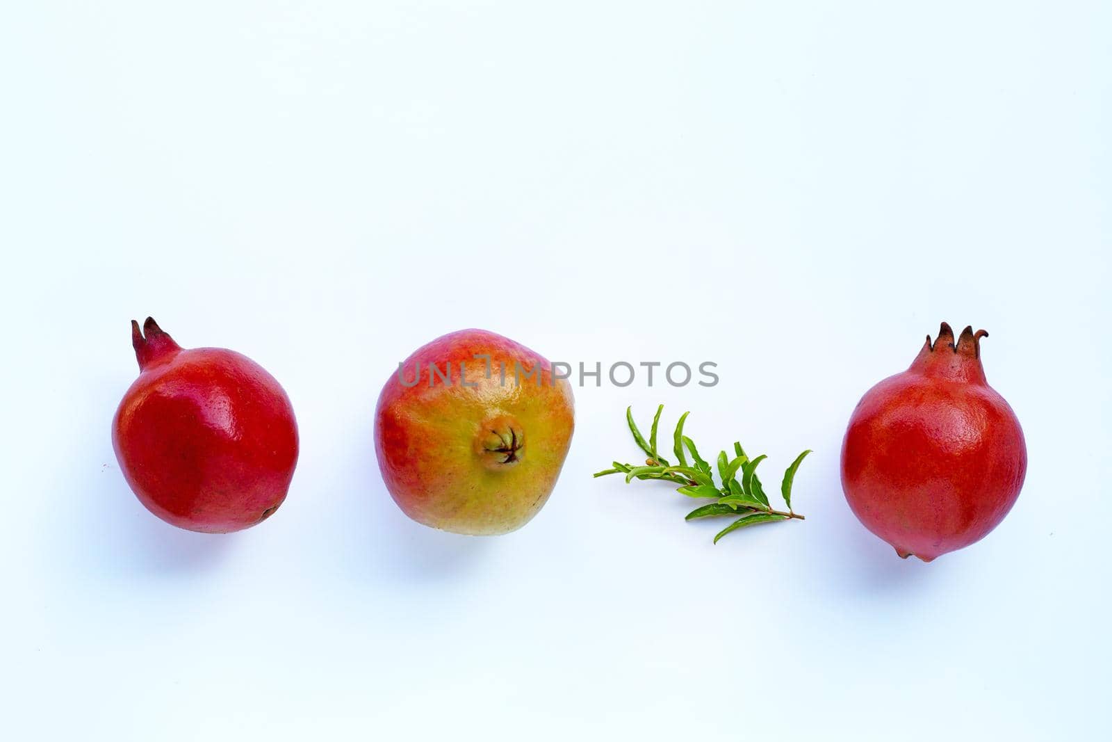 Top view of ripe pomegranate fruit with leaves on white