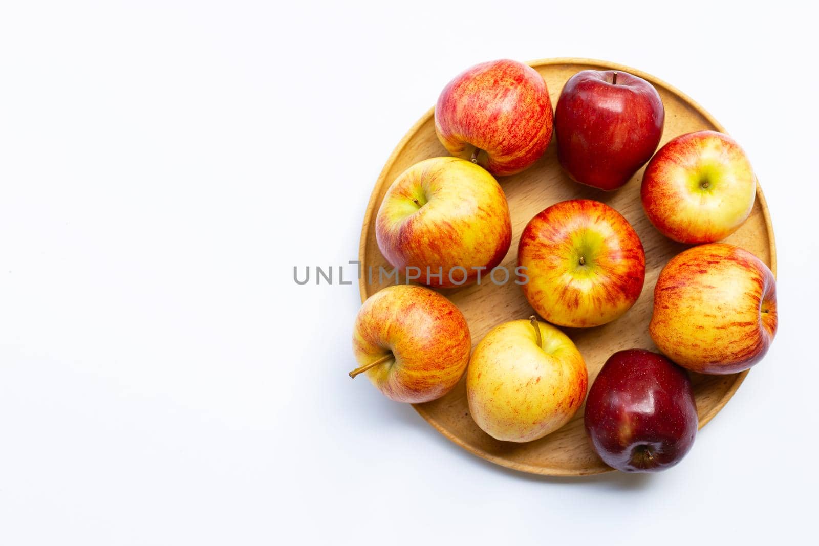 Fresh juicy apples on wooden plate on white background.
