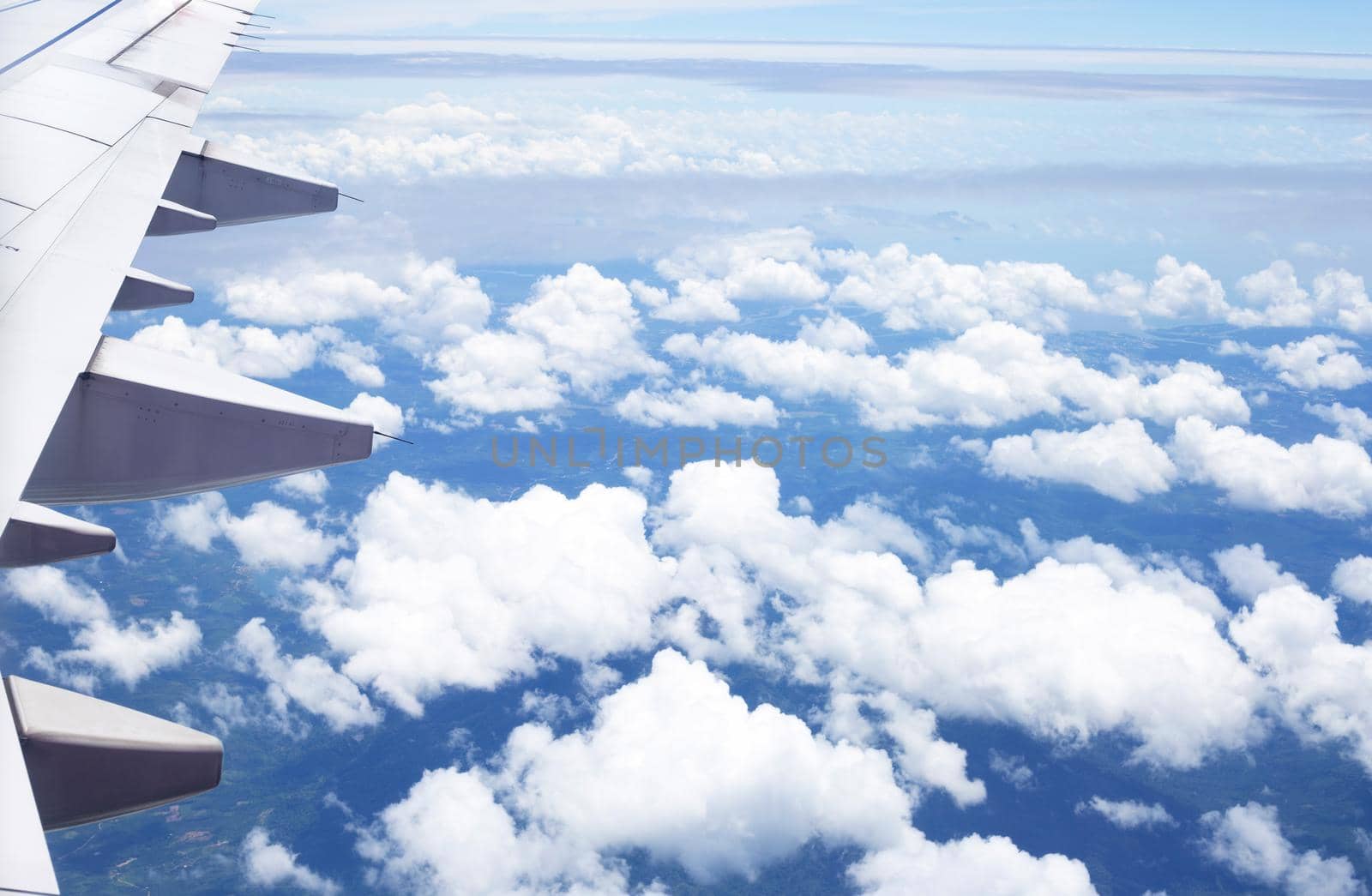 View of land, cloud and wing of airplane from window