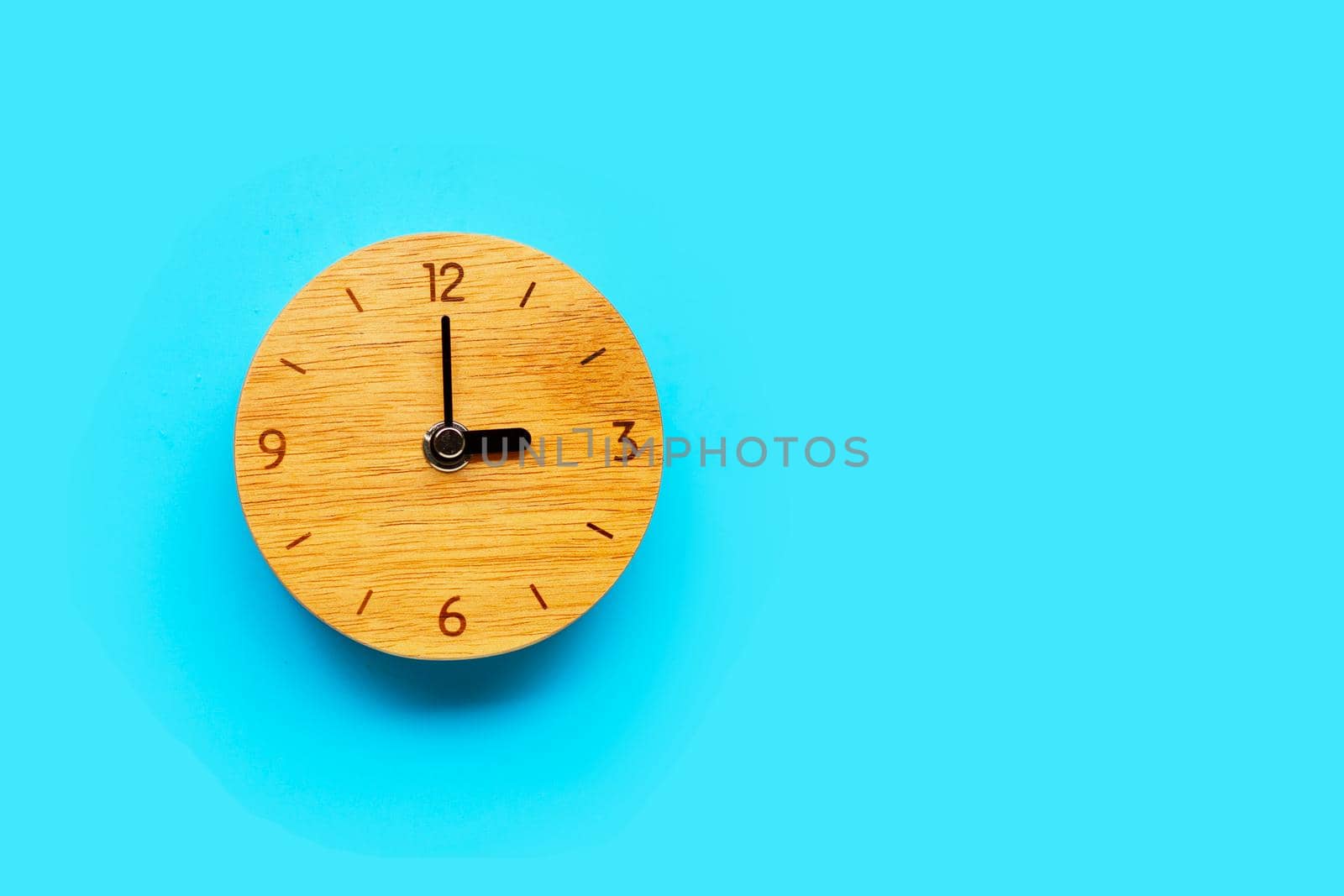 Wooden clock on blue background. Copy space