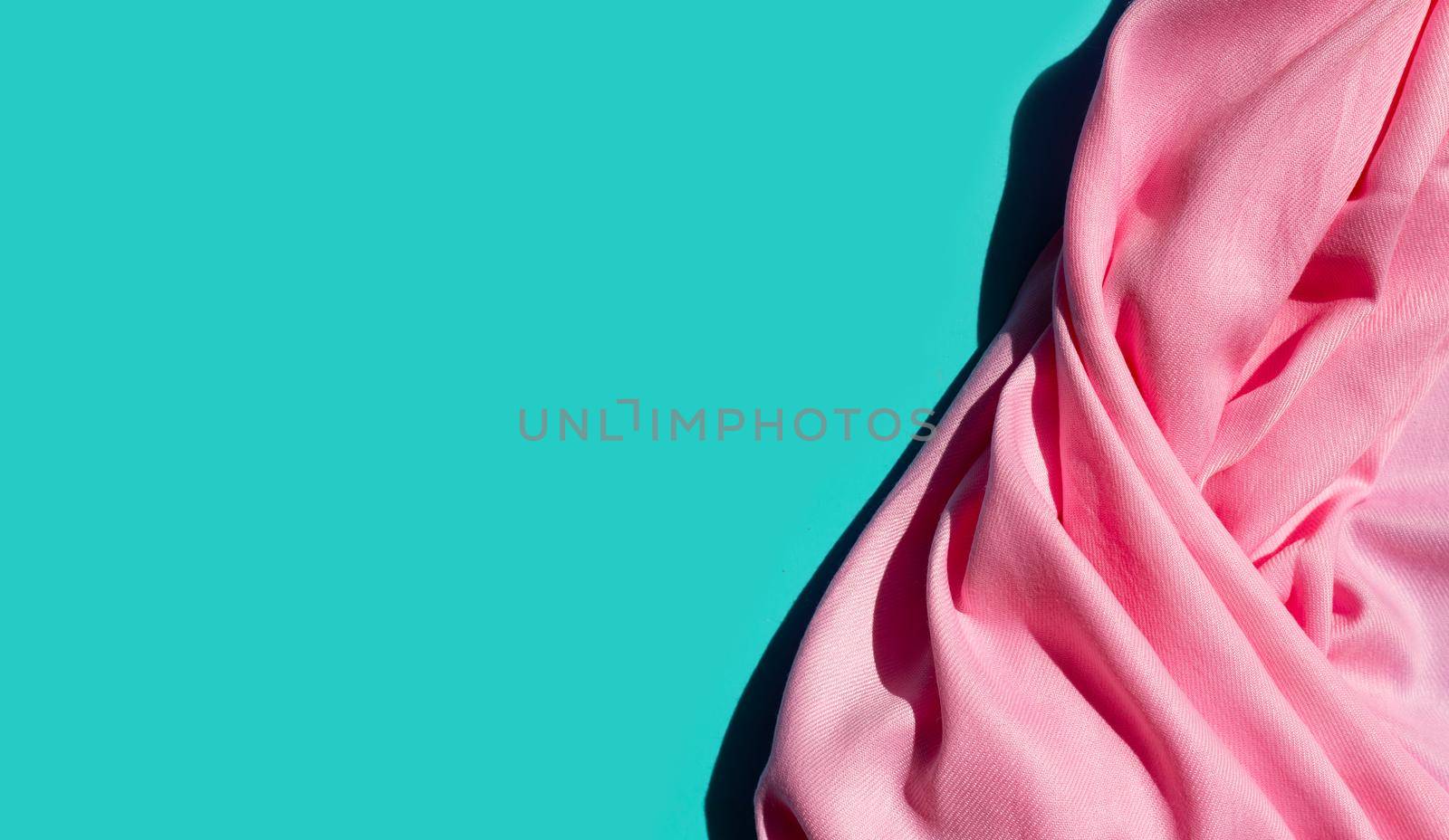 Pink women's shawl on blue background. Copy space