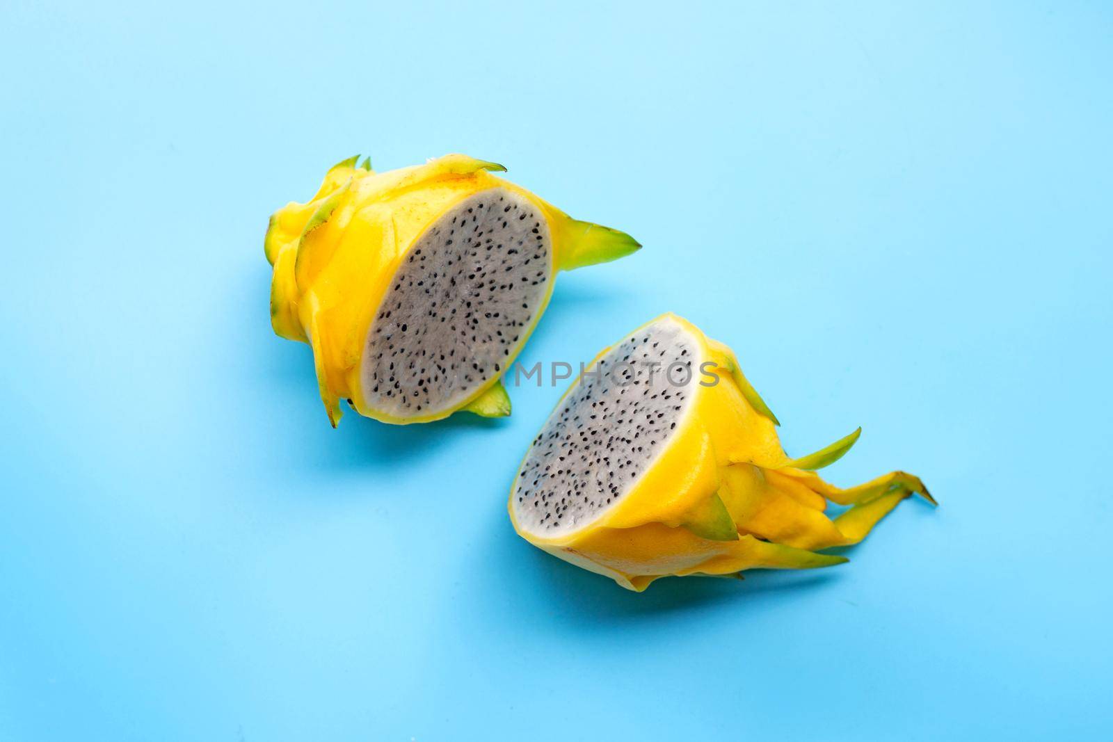 Yellow pitahaya or dragon fruit on white plate on blue background. Copy space