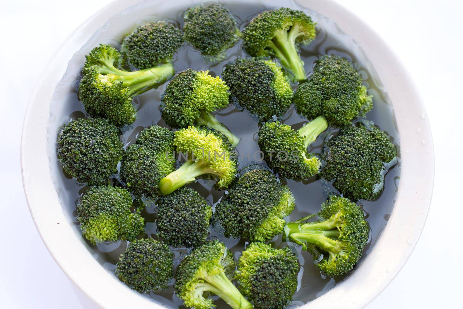 Fresh broccoli soaked in a white bowl of water