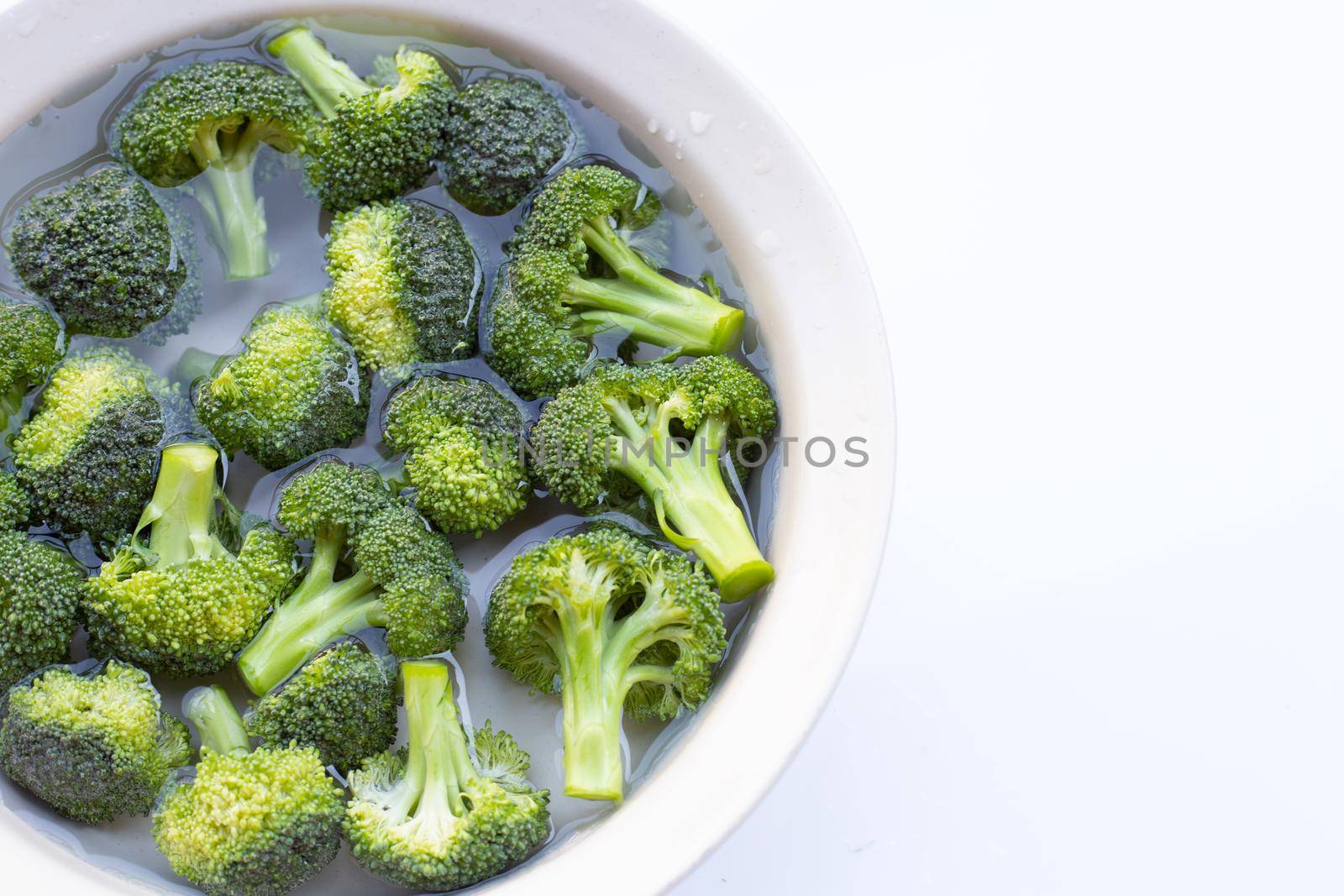 Fresh broccoli soaked in a white bowl of water